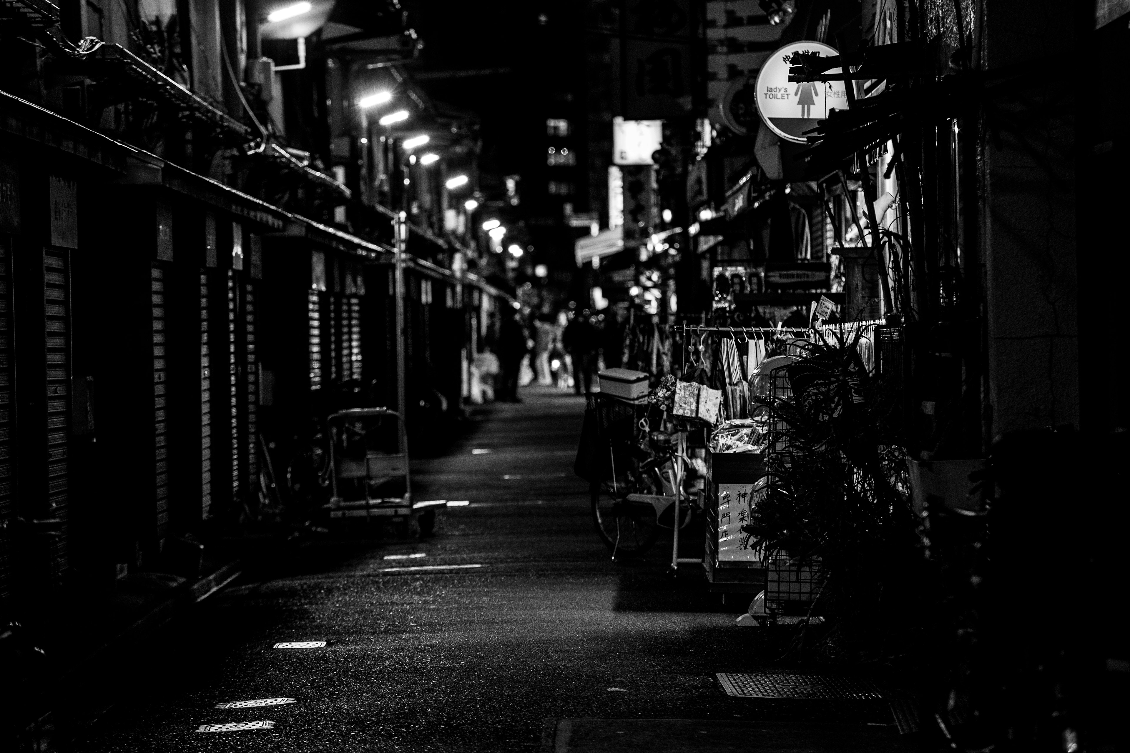 Calle oscura con escaparates iluminados y personas caminando