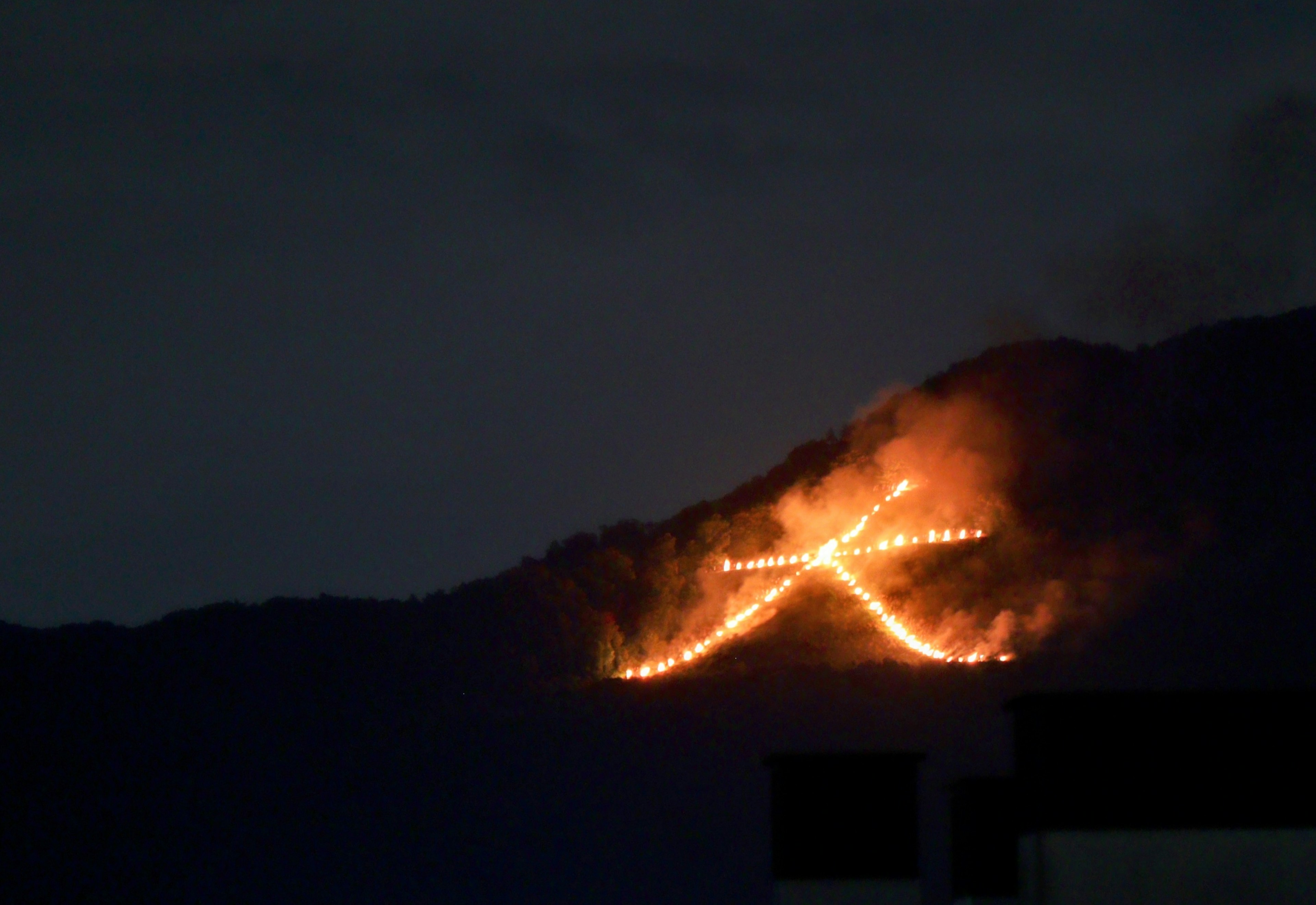 Símbolo ardiente iluminado en una montaña por la noche