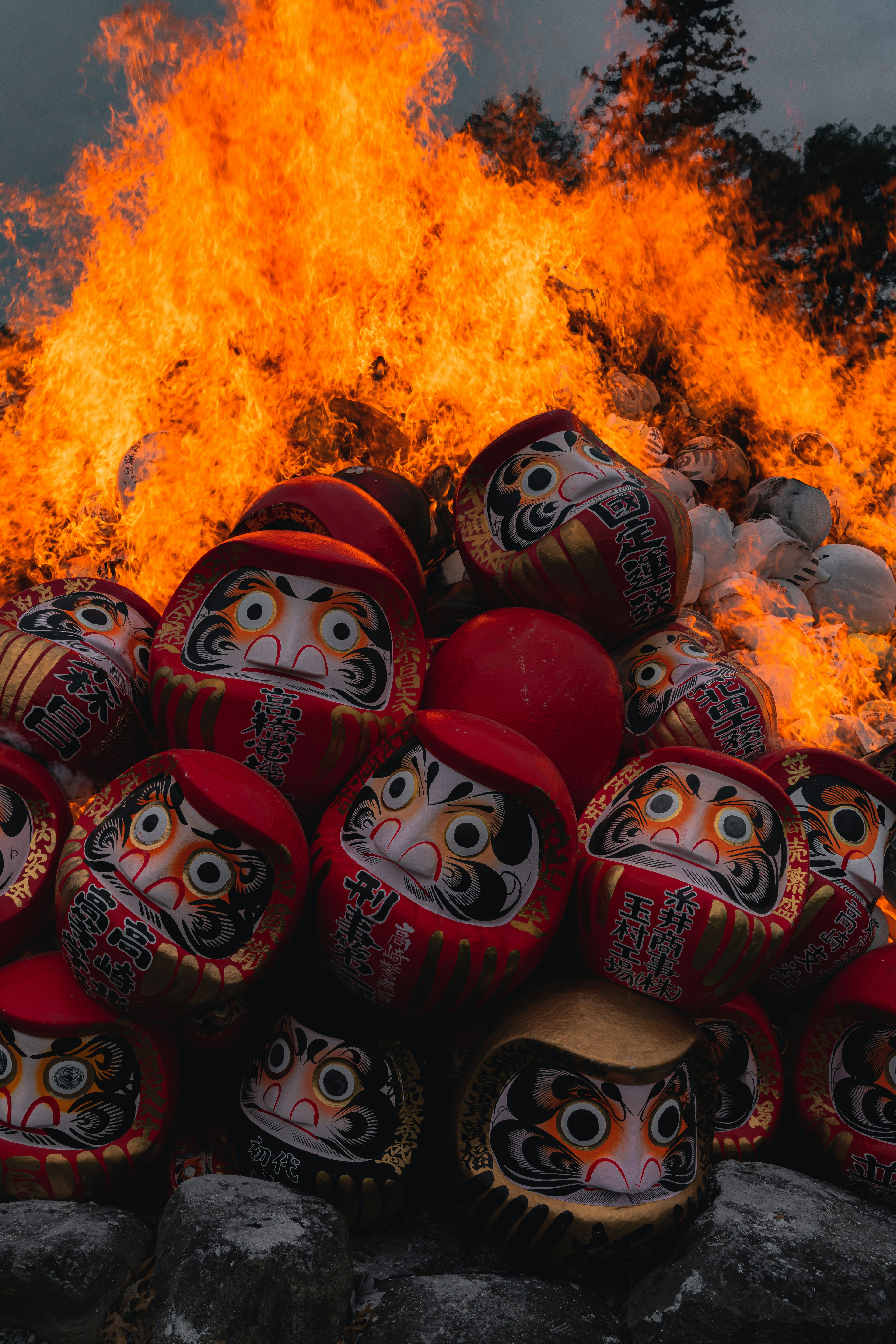 Boneka daruma merah ditumpuk dalam api