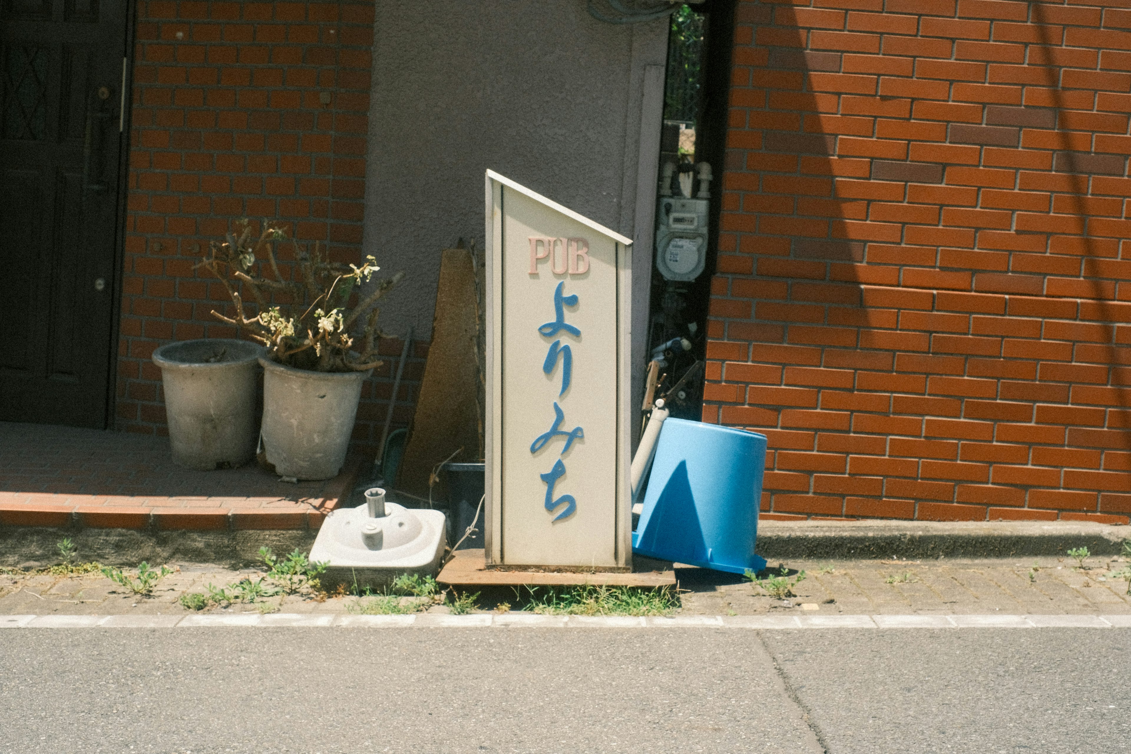 赤いレンガの壁の前に立つ看板と青い椅子のある風景