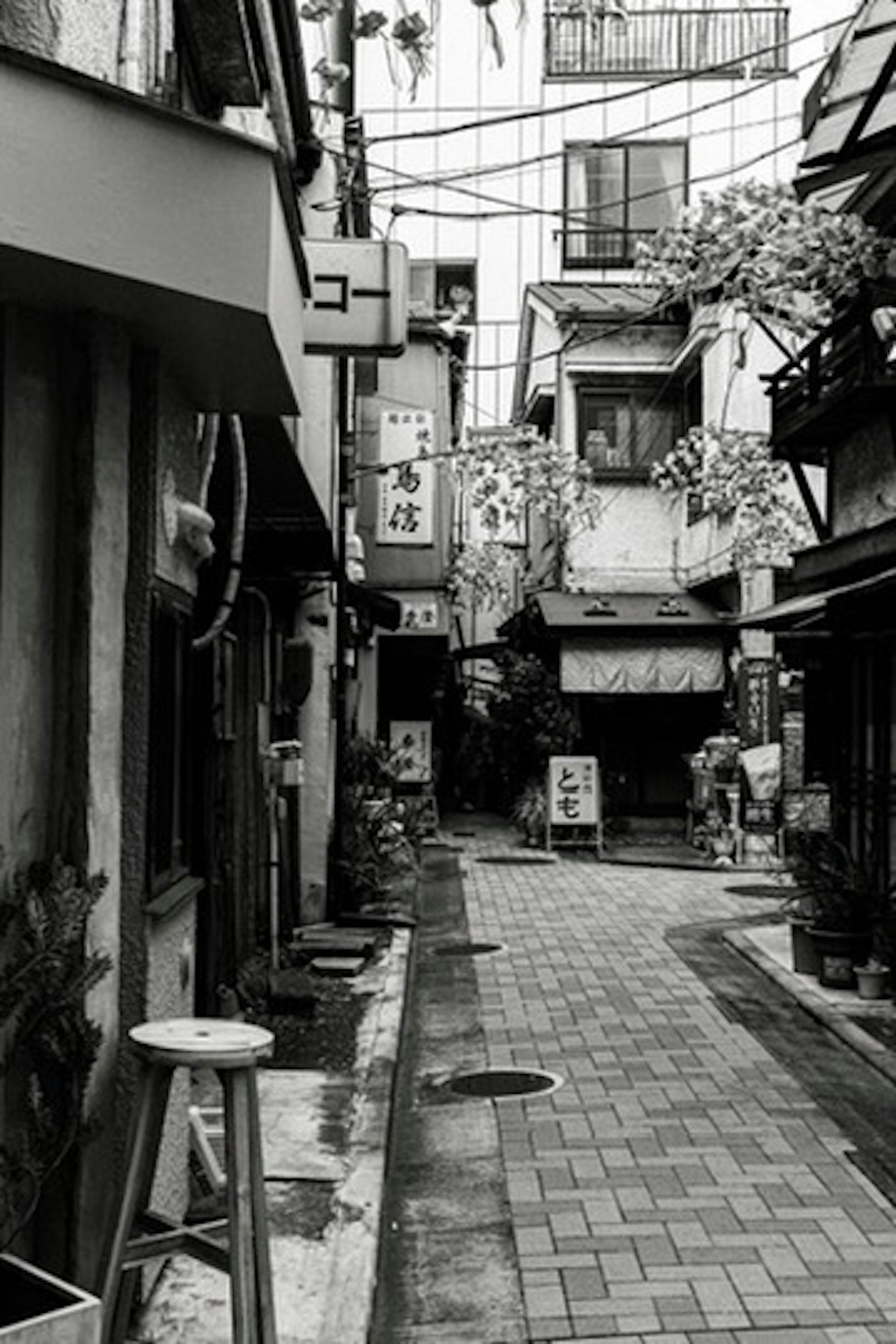 Cortile stretto in bianco e nero con edifici antichi e insegne