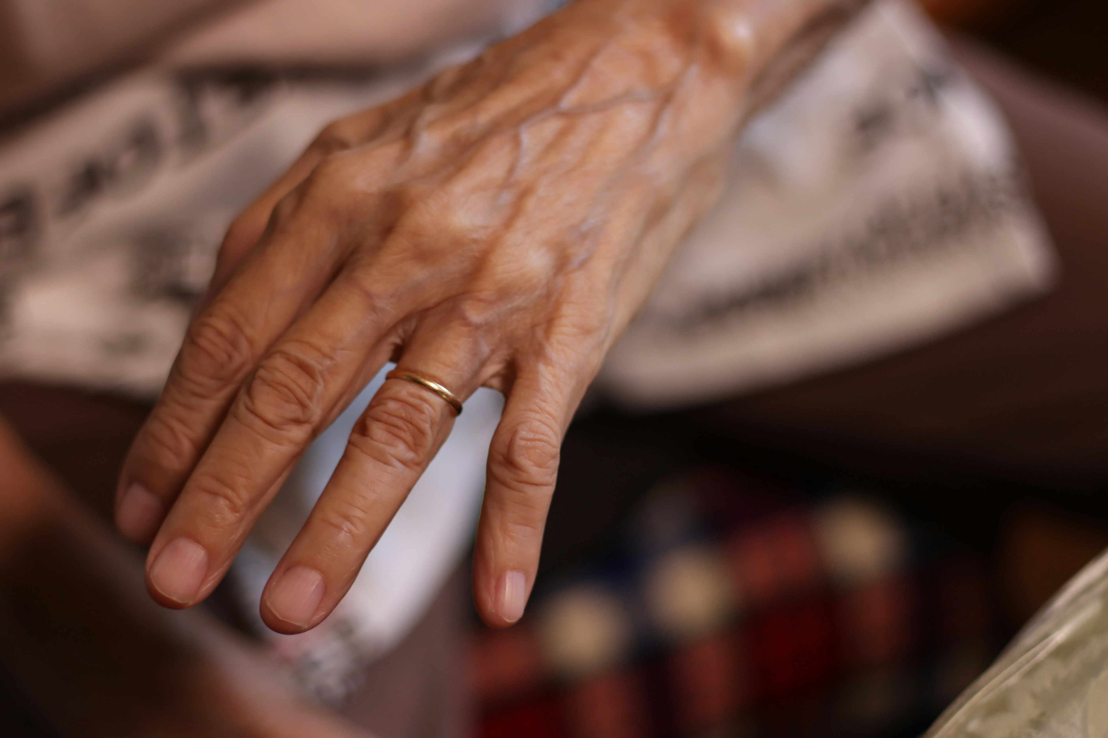 An elderly hand wearing a ring with visible veins and texture