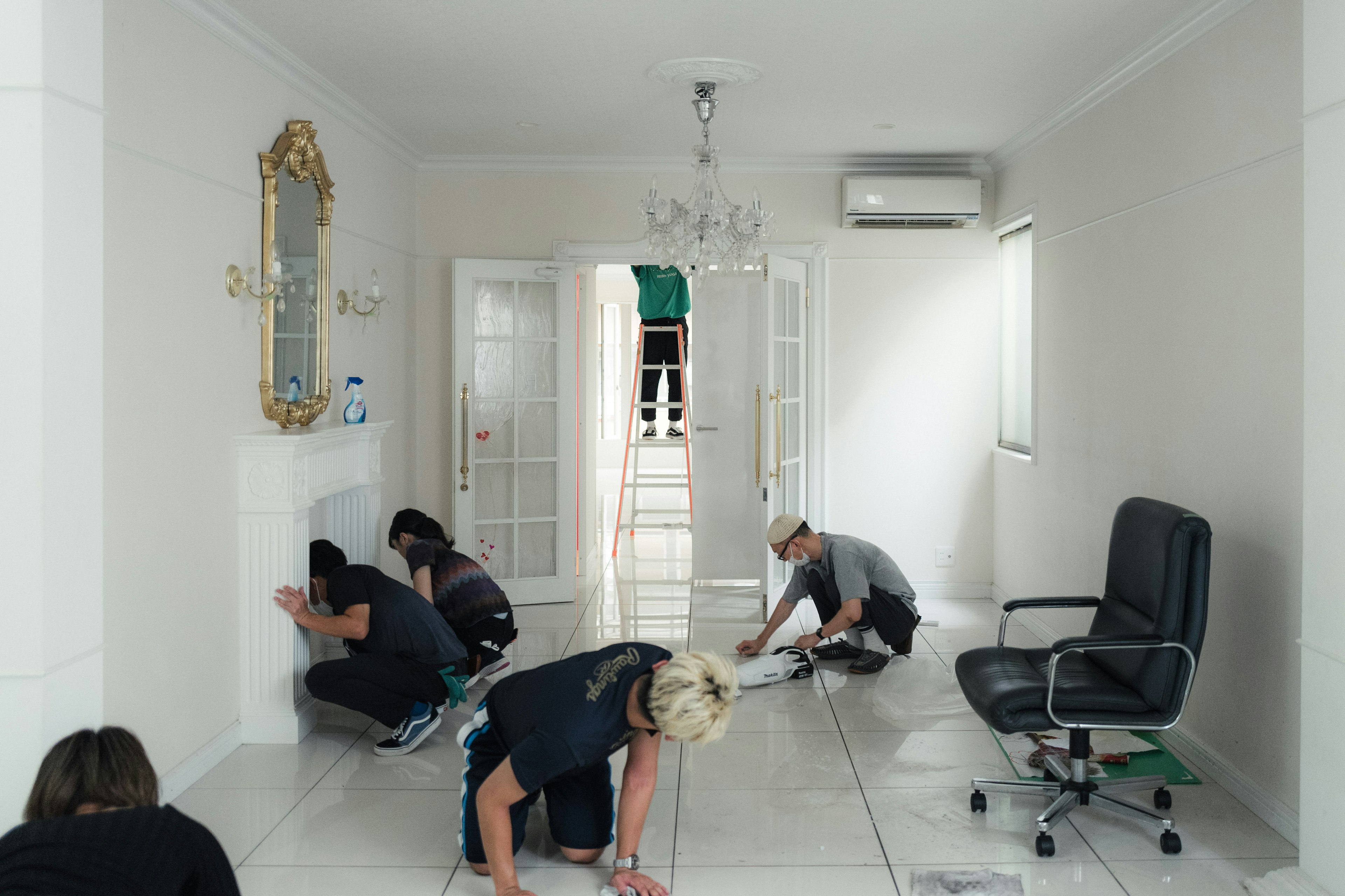 Several people cleaning in a room with white walls