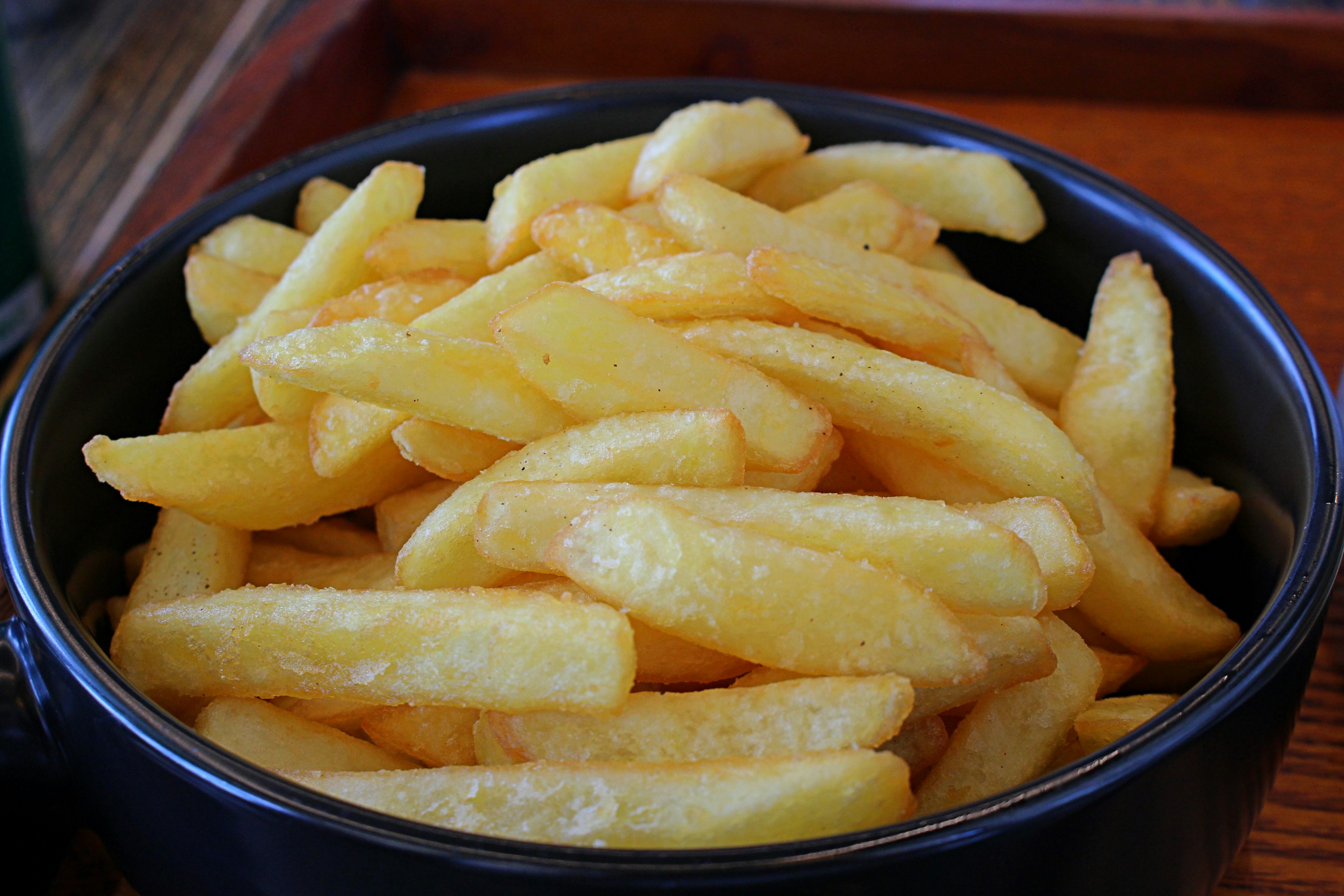 Crispy French fries piled in a black bowl