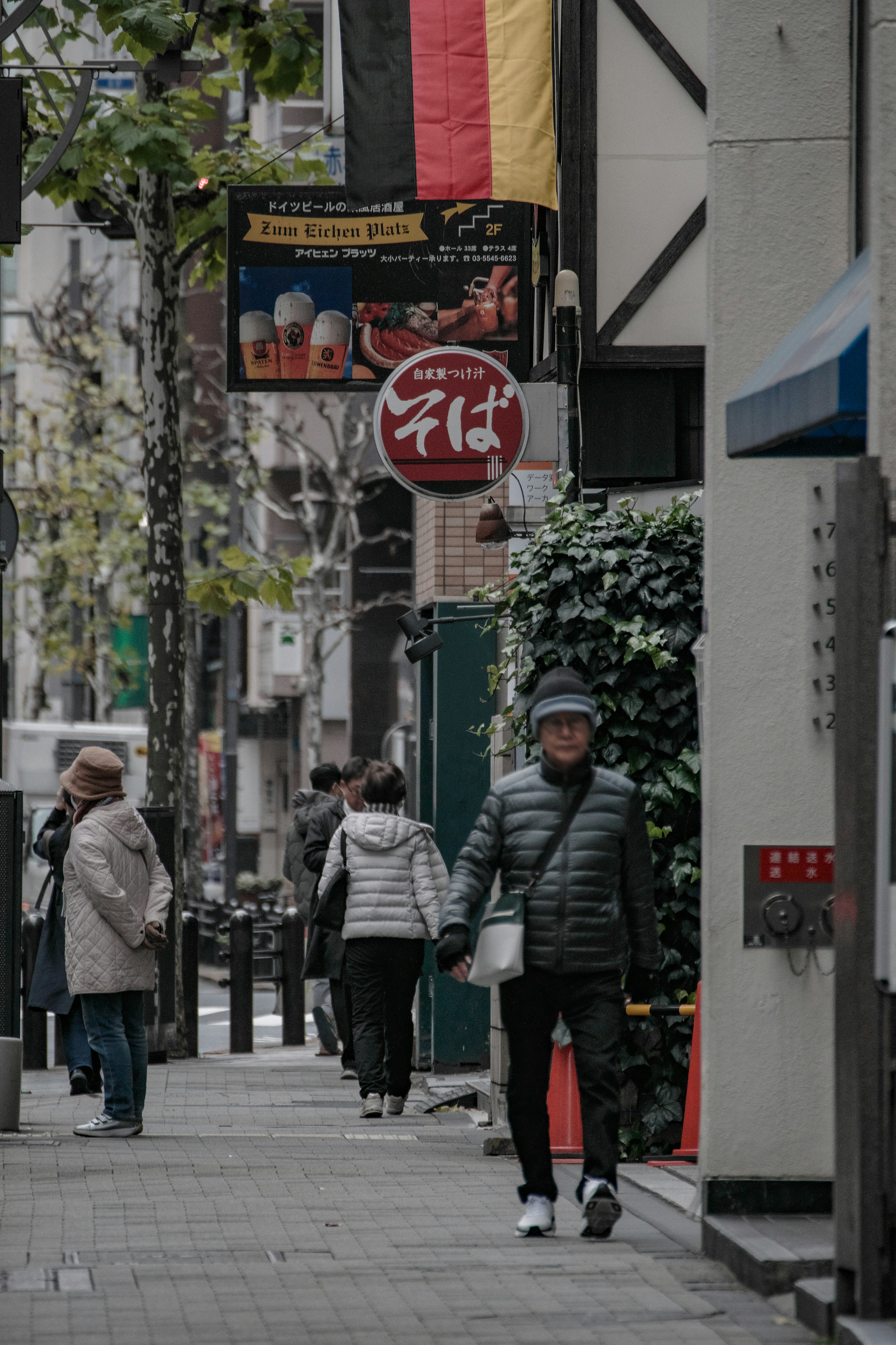 Scène urbaine avec des personnes marchant et un drapeau allemand affiché