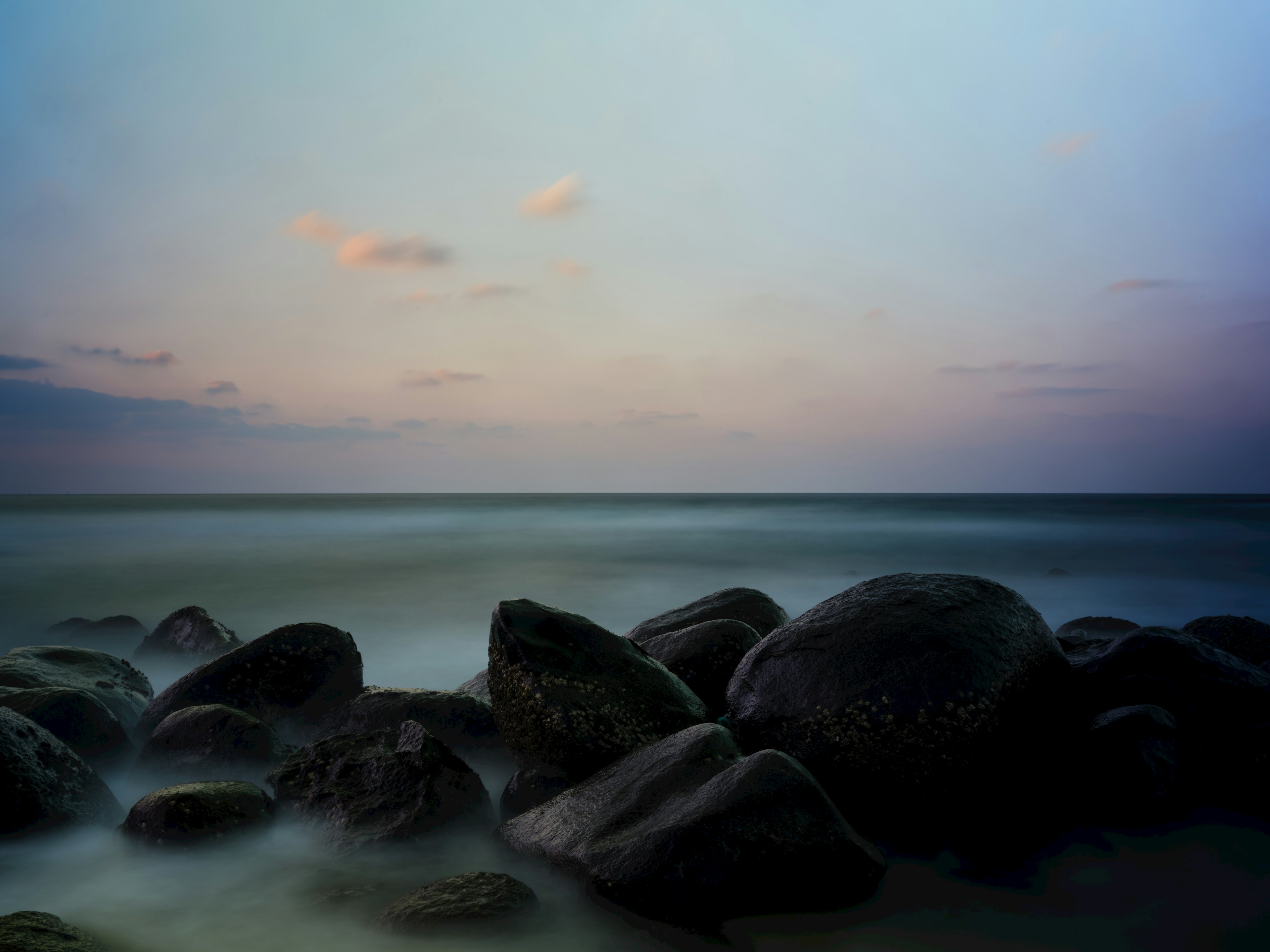 Pemandangan pantai dengan batu dan laut tenang