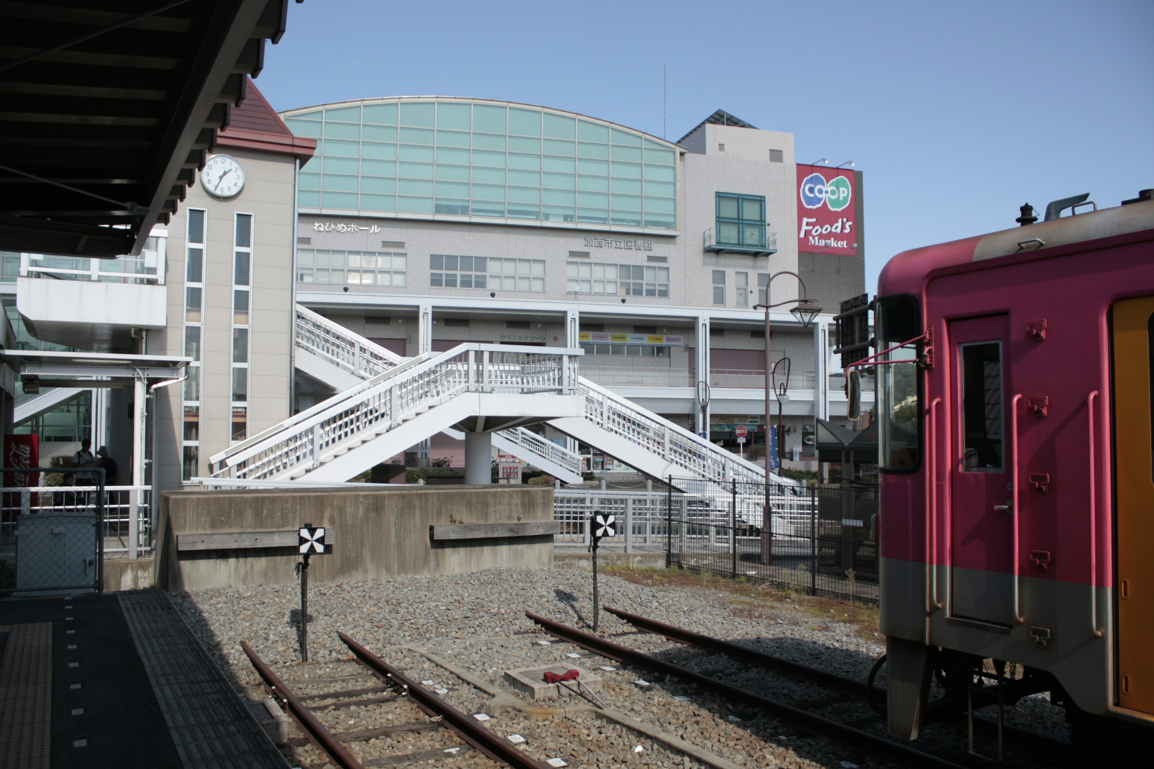 Szene mit einem rosa Zug und einem Bahnhofsgebäude