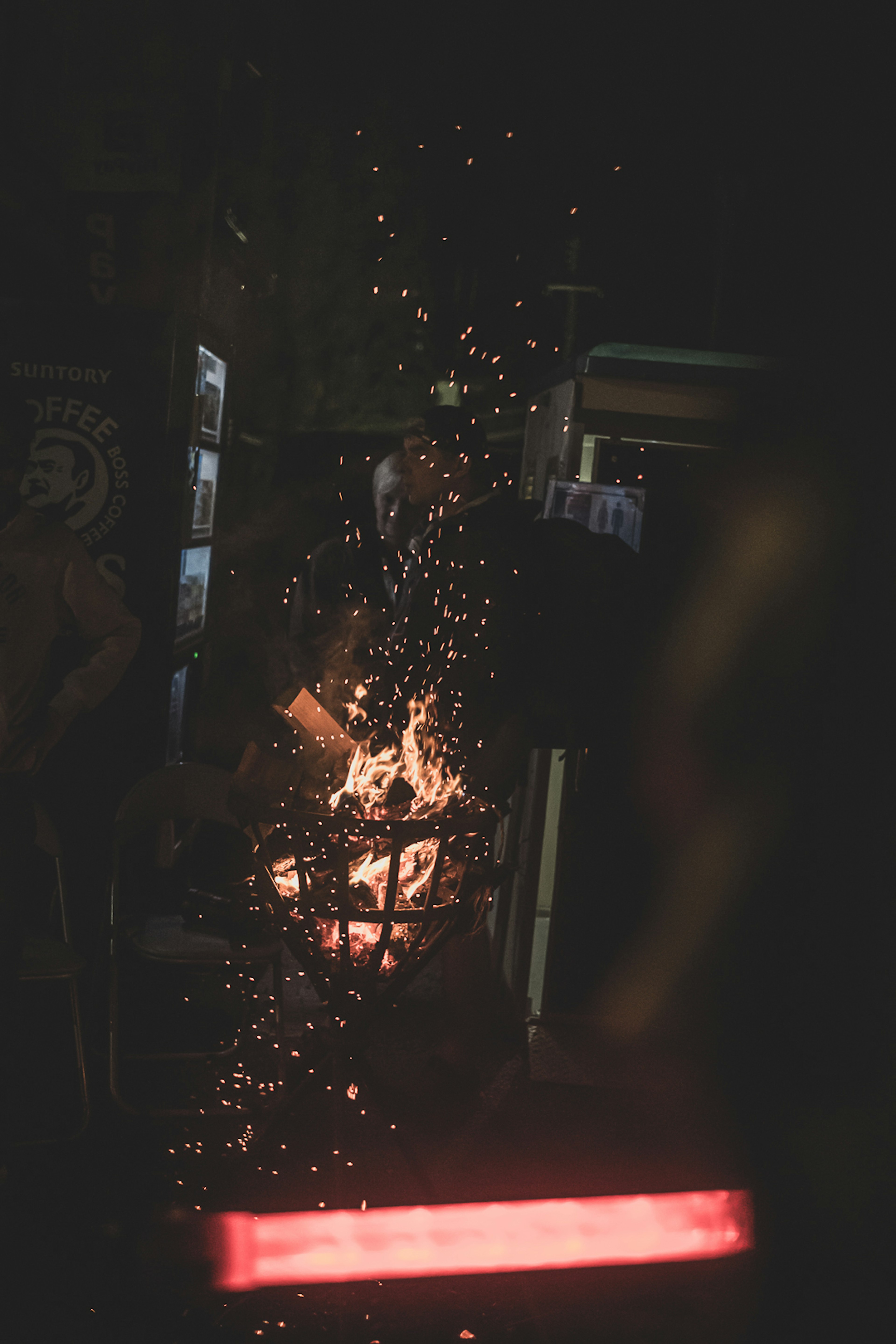 Scene near a bonfire with sparks rising against a dark background