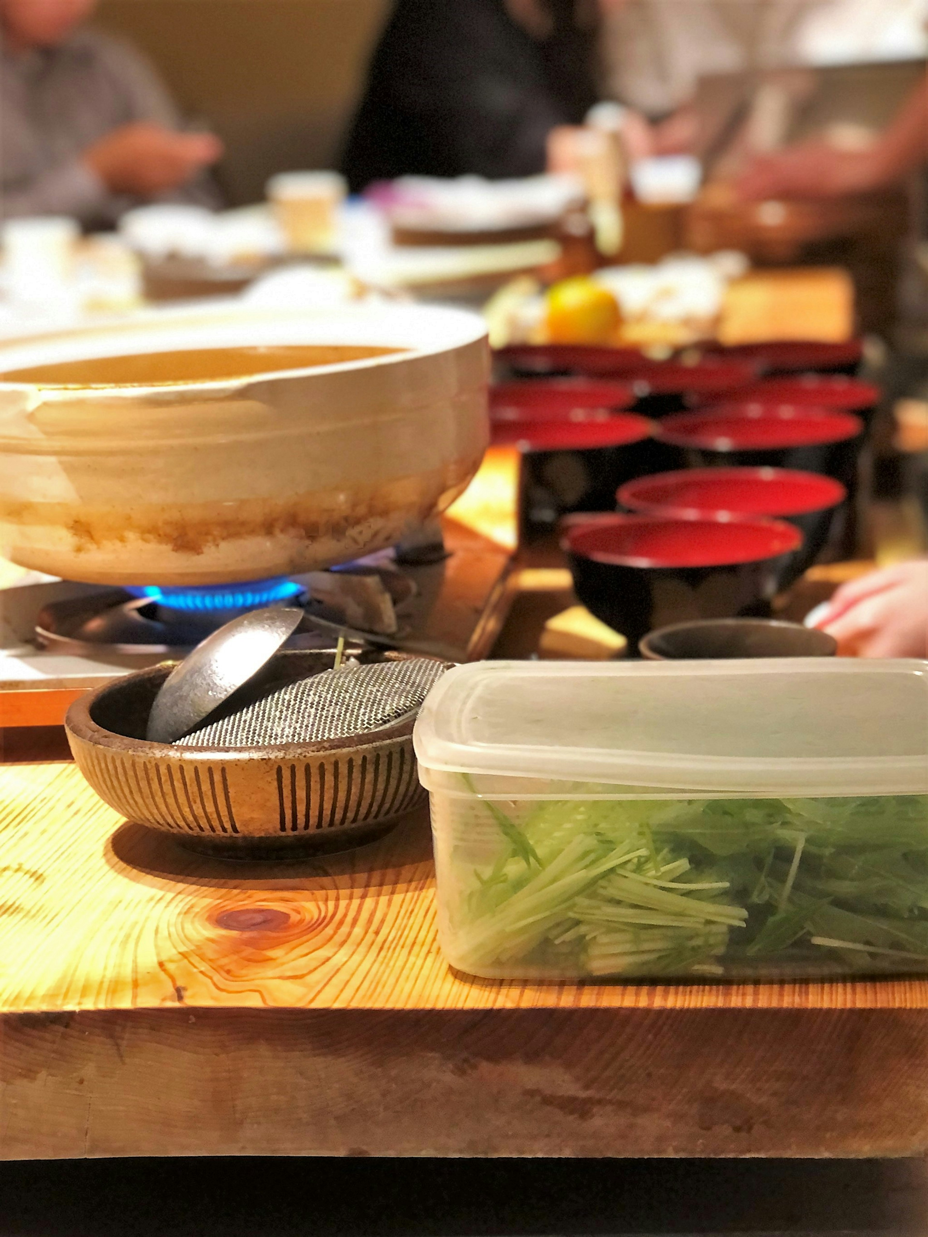 Table set with a hot pot and red bowls Various vegetables and cooking utensils displayed