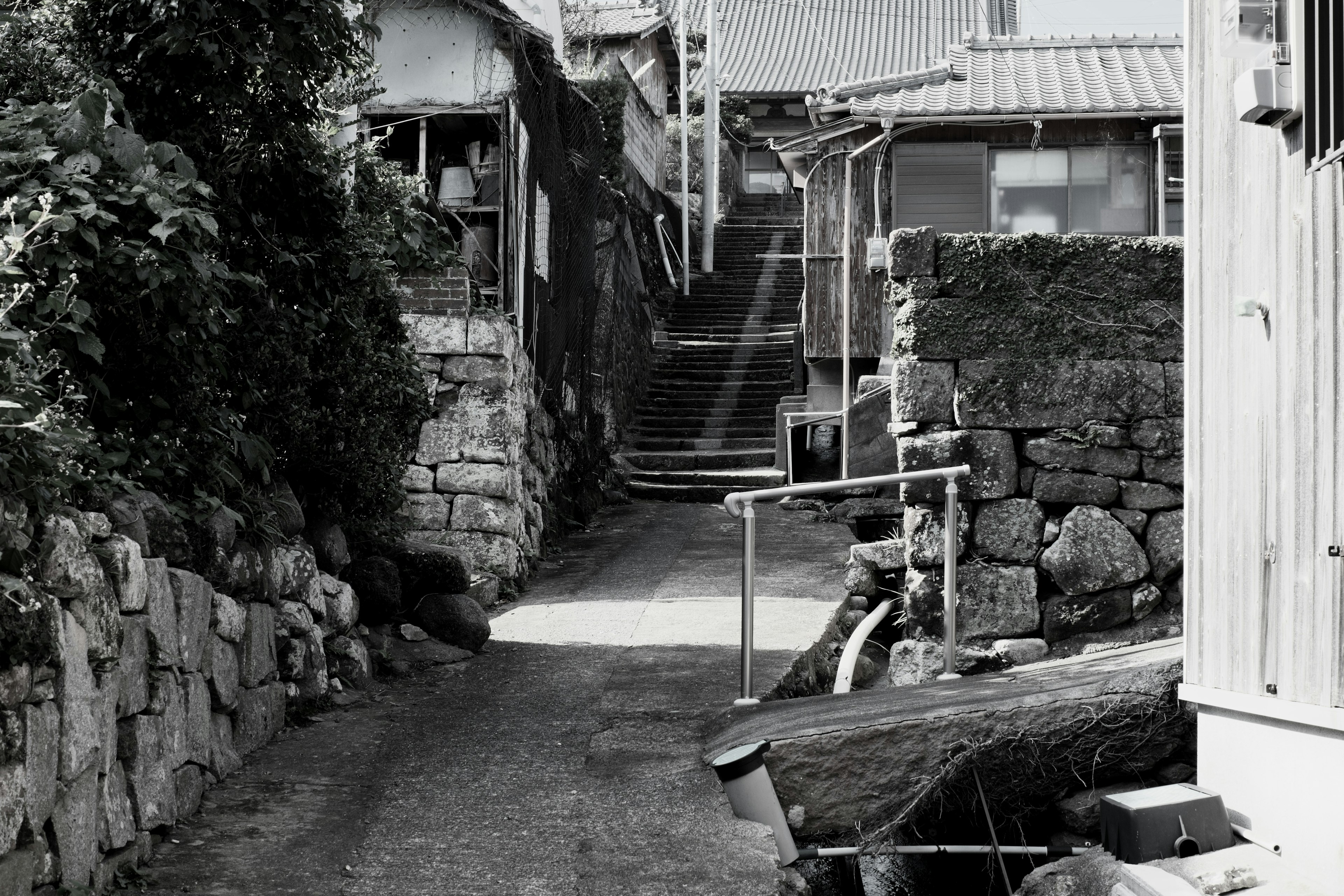 Callejón estrecho con casas antiguas y muros de piedra en blanco y negro