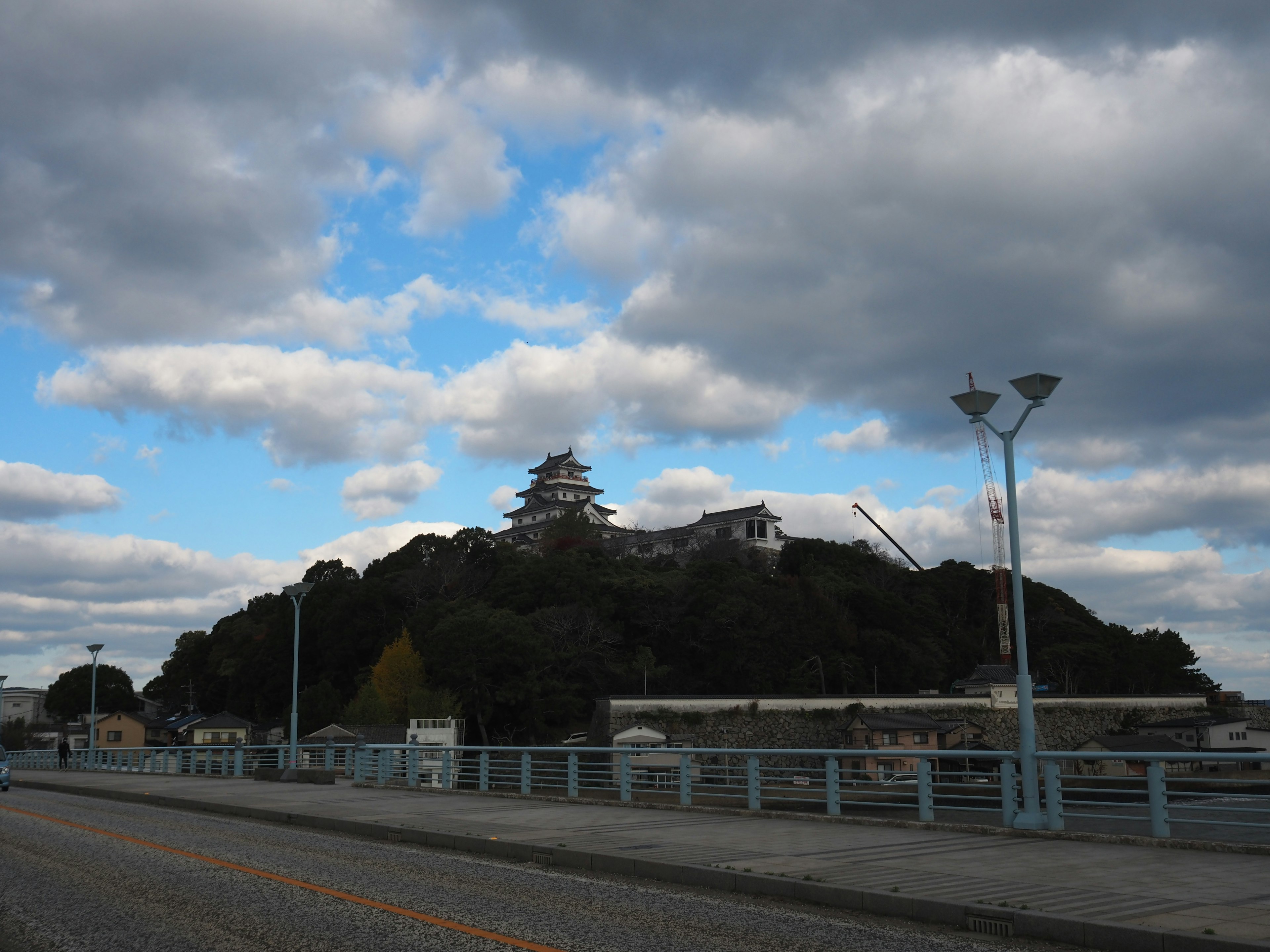 青空の下にそびえる城と緑の木々が見える風景