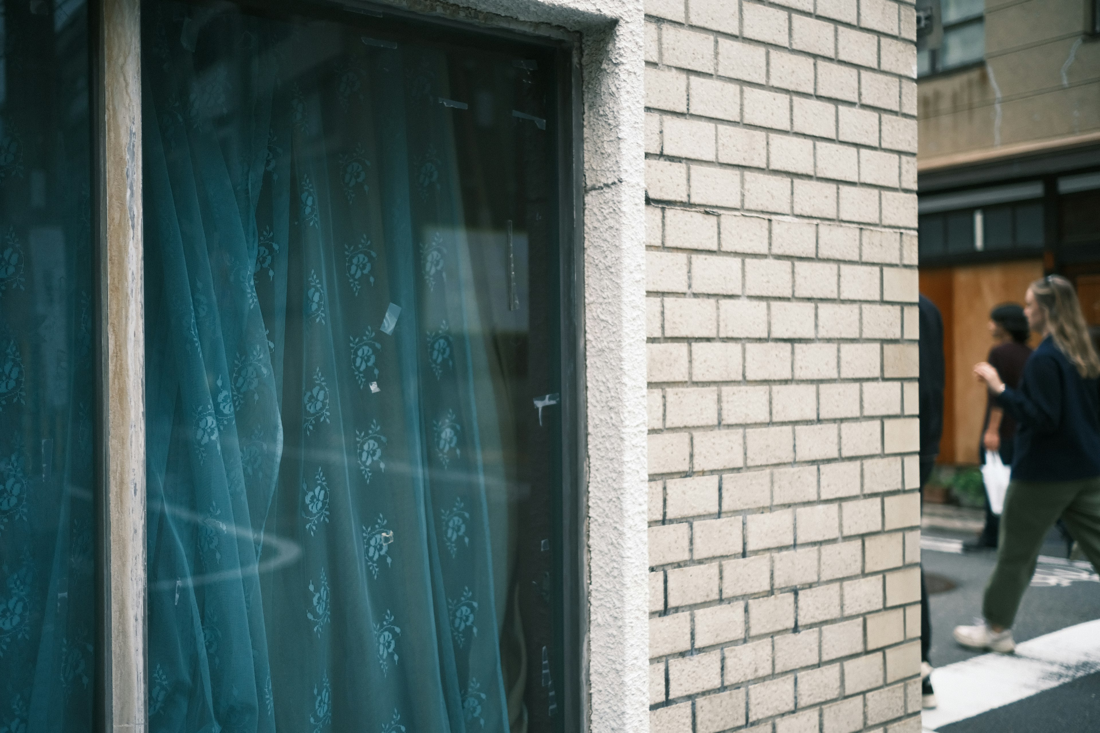 Fenster mit blauen Vorhängen und Ziegelmauer