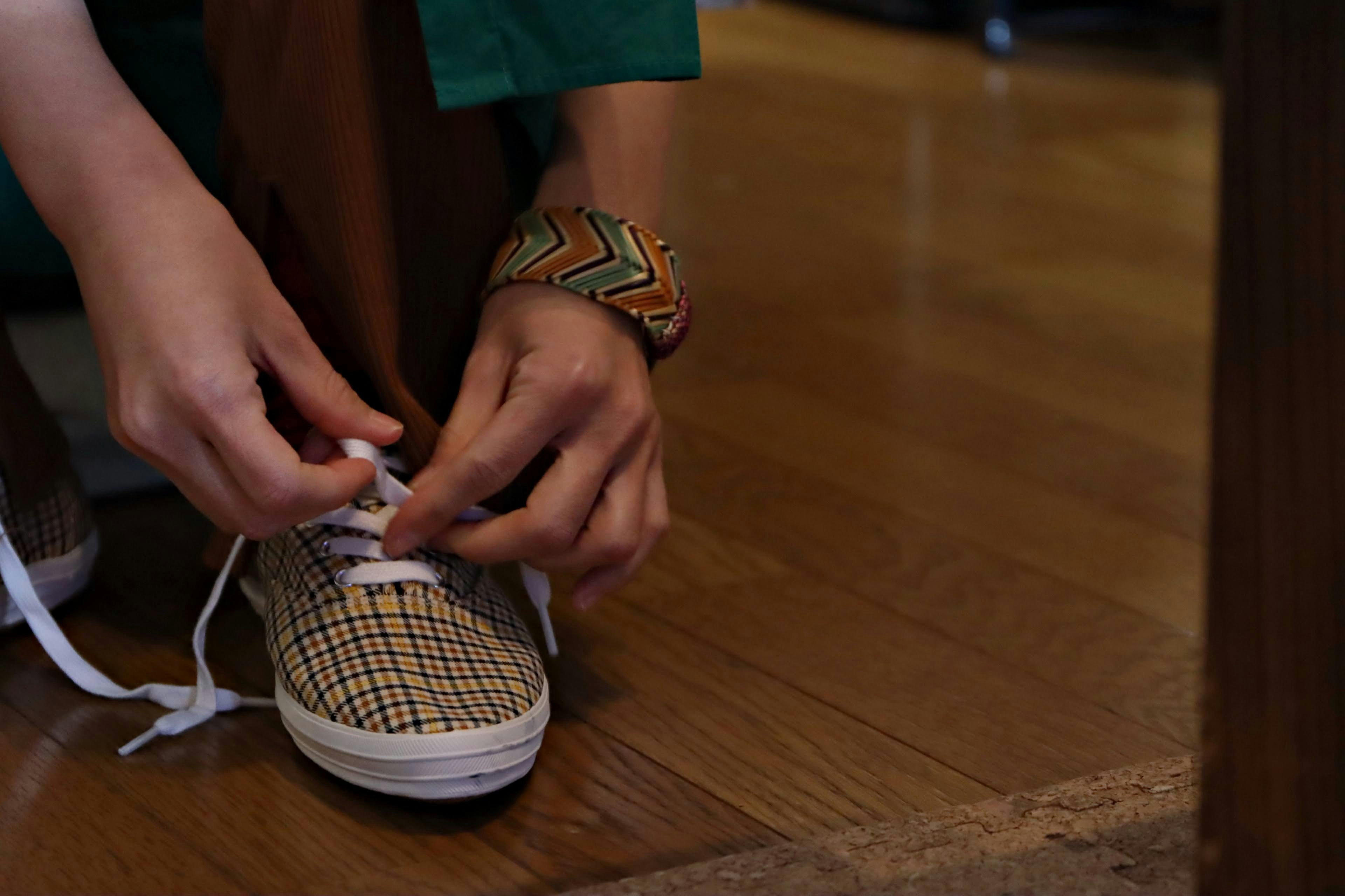 Close-up of hands tying shoelaces wearing a colorful bracelet