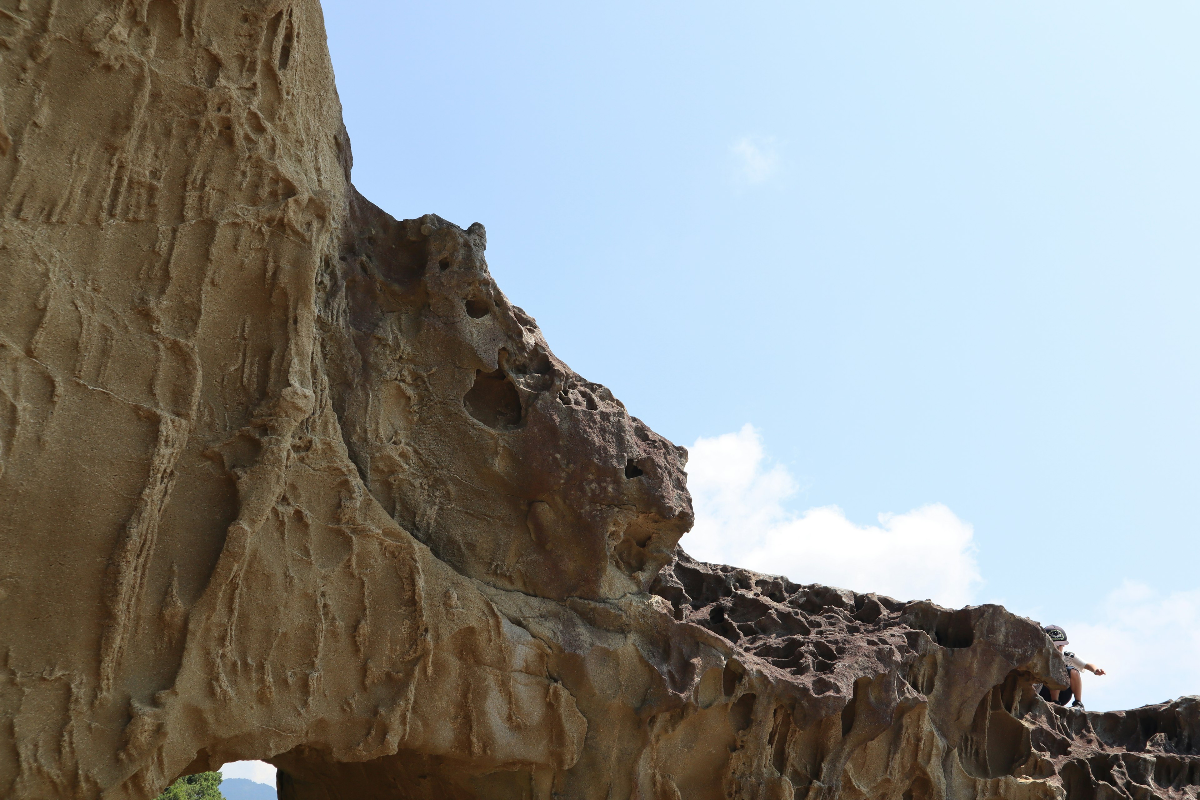 An unusual rock formation resembling a natural sculpture under a blue sky