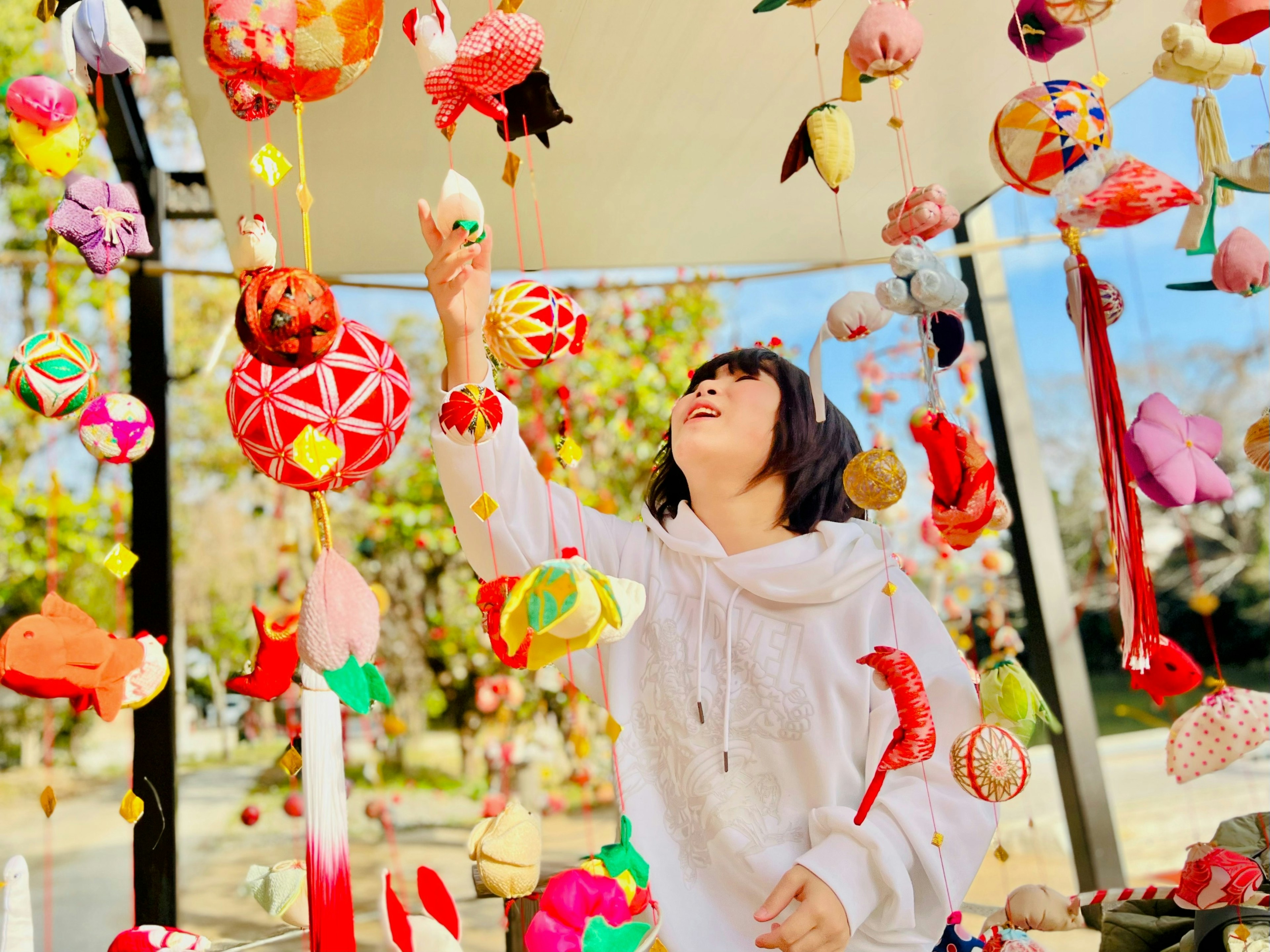 A woman interacting with colorful hanging decorations traditional Japanese ornaments displayed at a stall