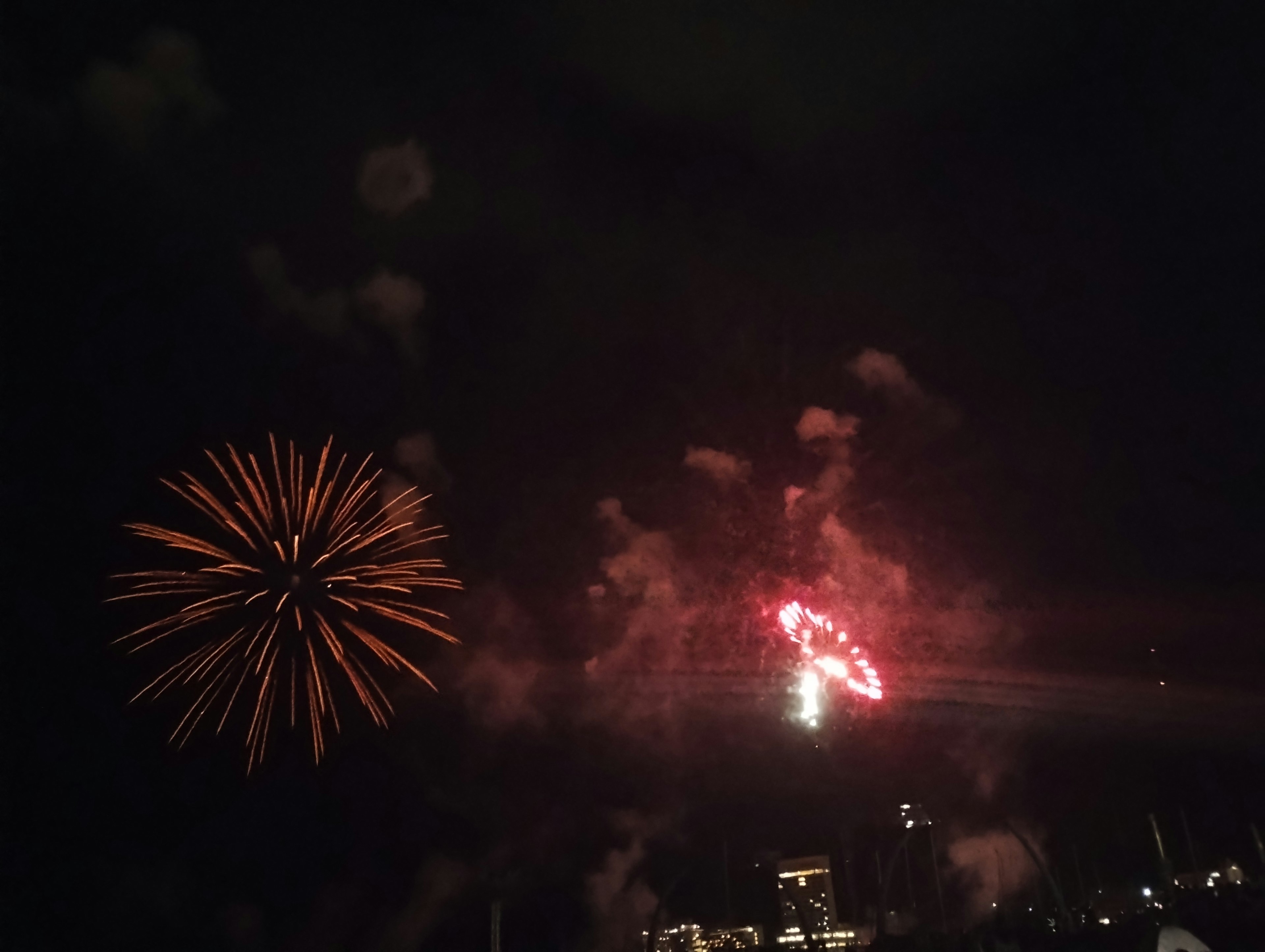 Espectáculo de fuegos artificiales en el cielo nocturno con colores rojos y naranjas