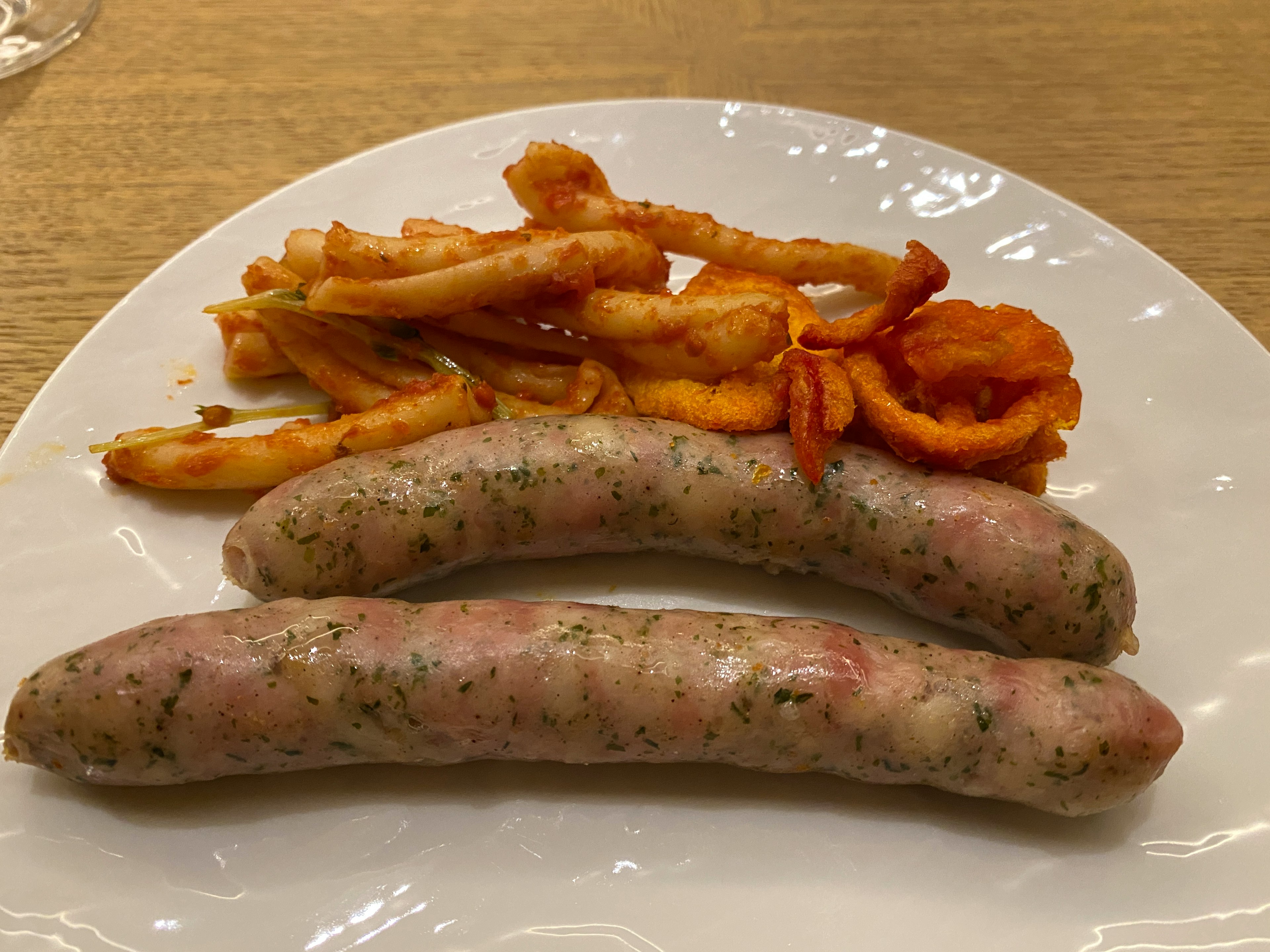 Zwei Würstchen und Pommes auf einem weißen Teller