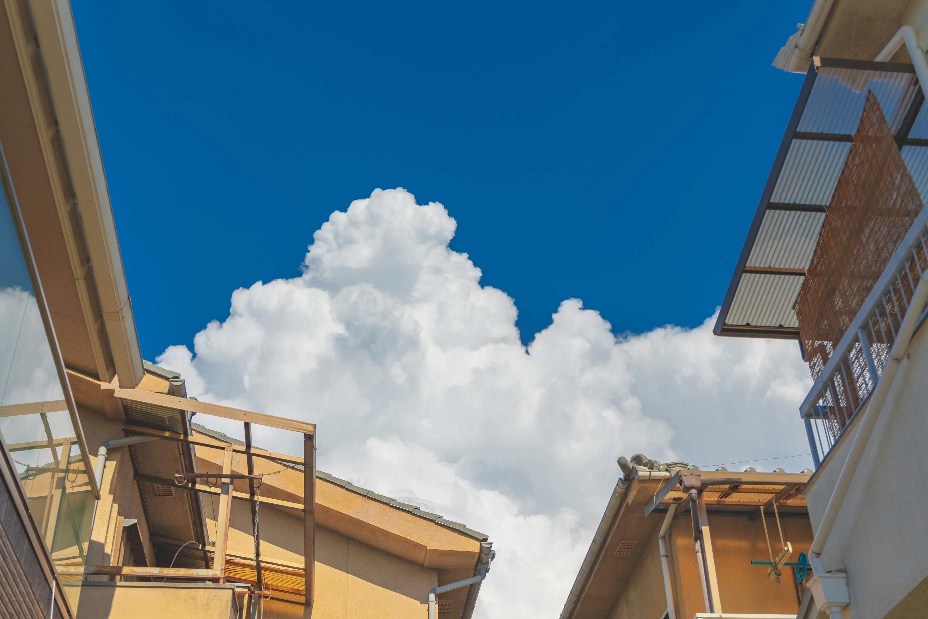 Blick zwischen Gebäuden mit blauem Himmel und flauschigen weißen Wolken