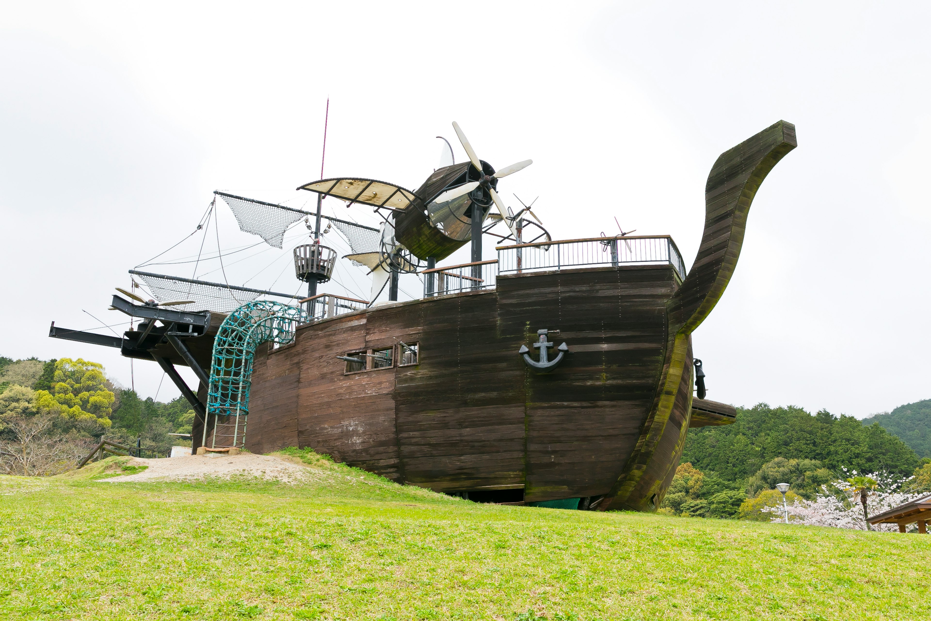 Ein Spielplatz in Form eines Holzschiffs auf einem grasbewachsenen Gelände