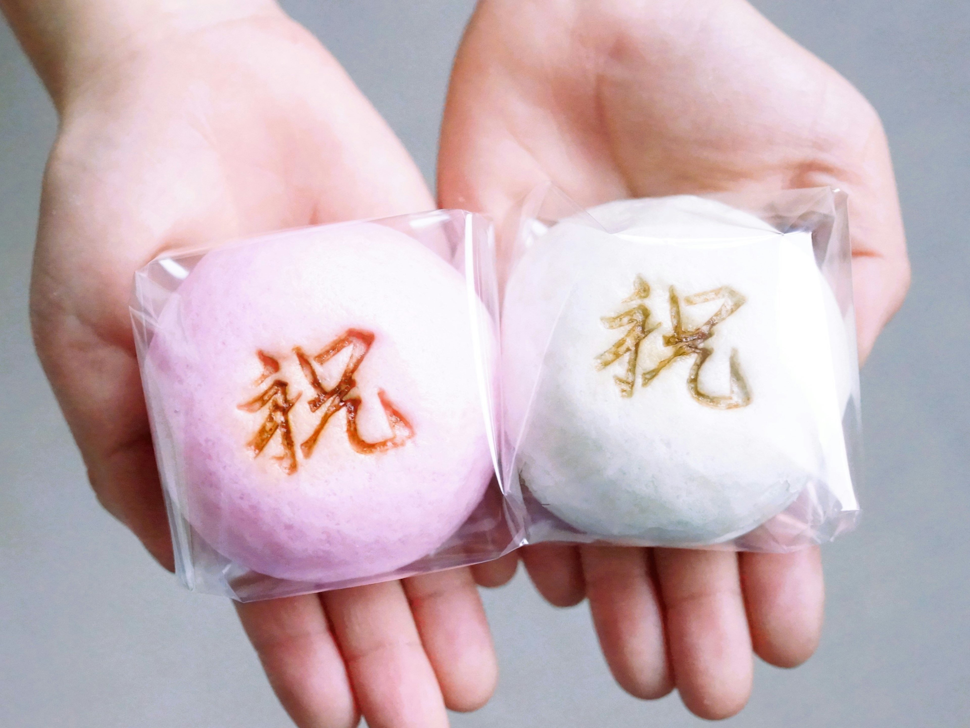 Mains tenant des bonbons roses et blancs avec le caractère kanji pour célébration