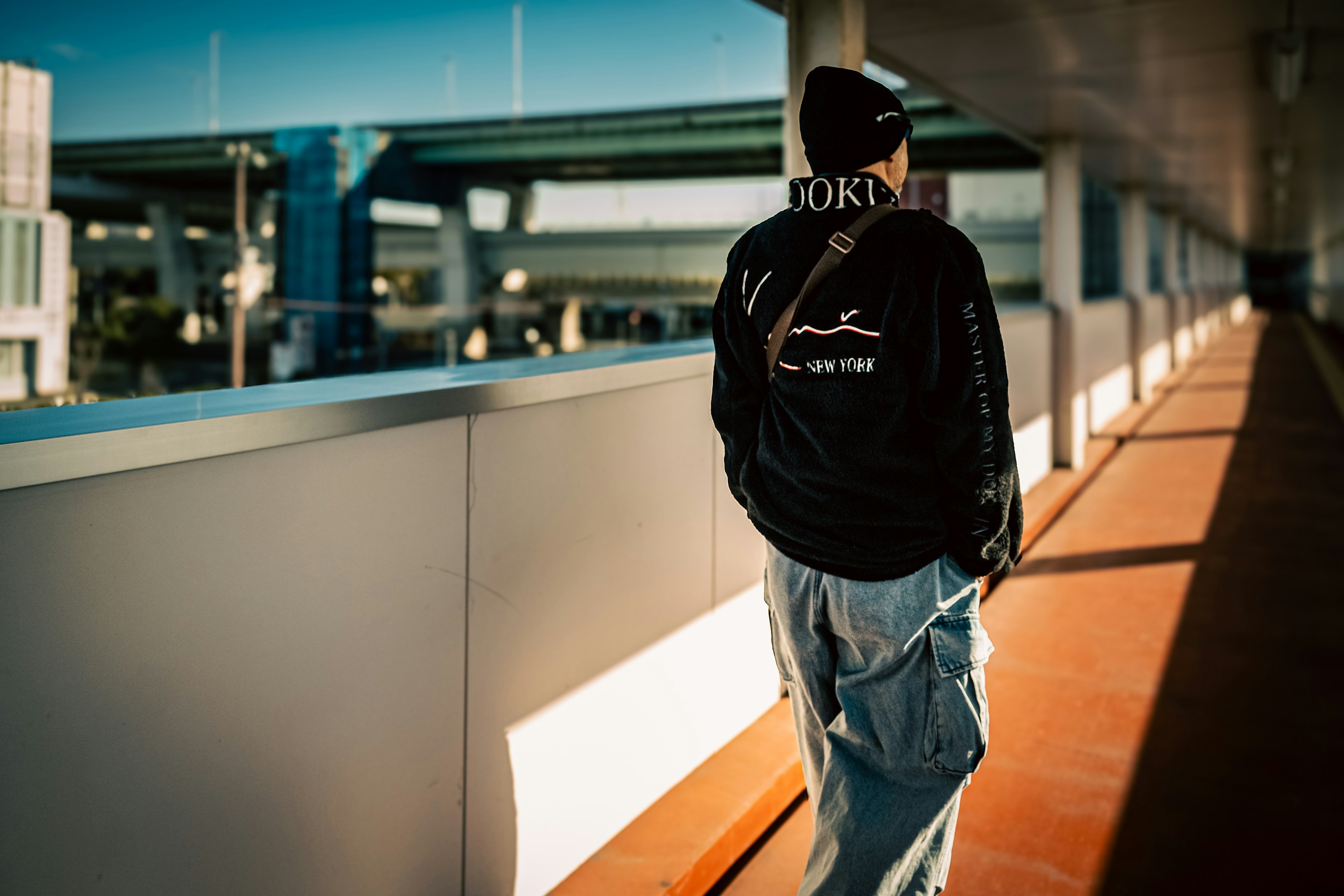 A man walking in a tunnel wearing a black jacket and denim pants