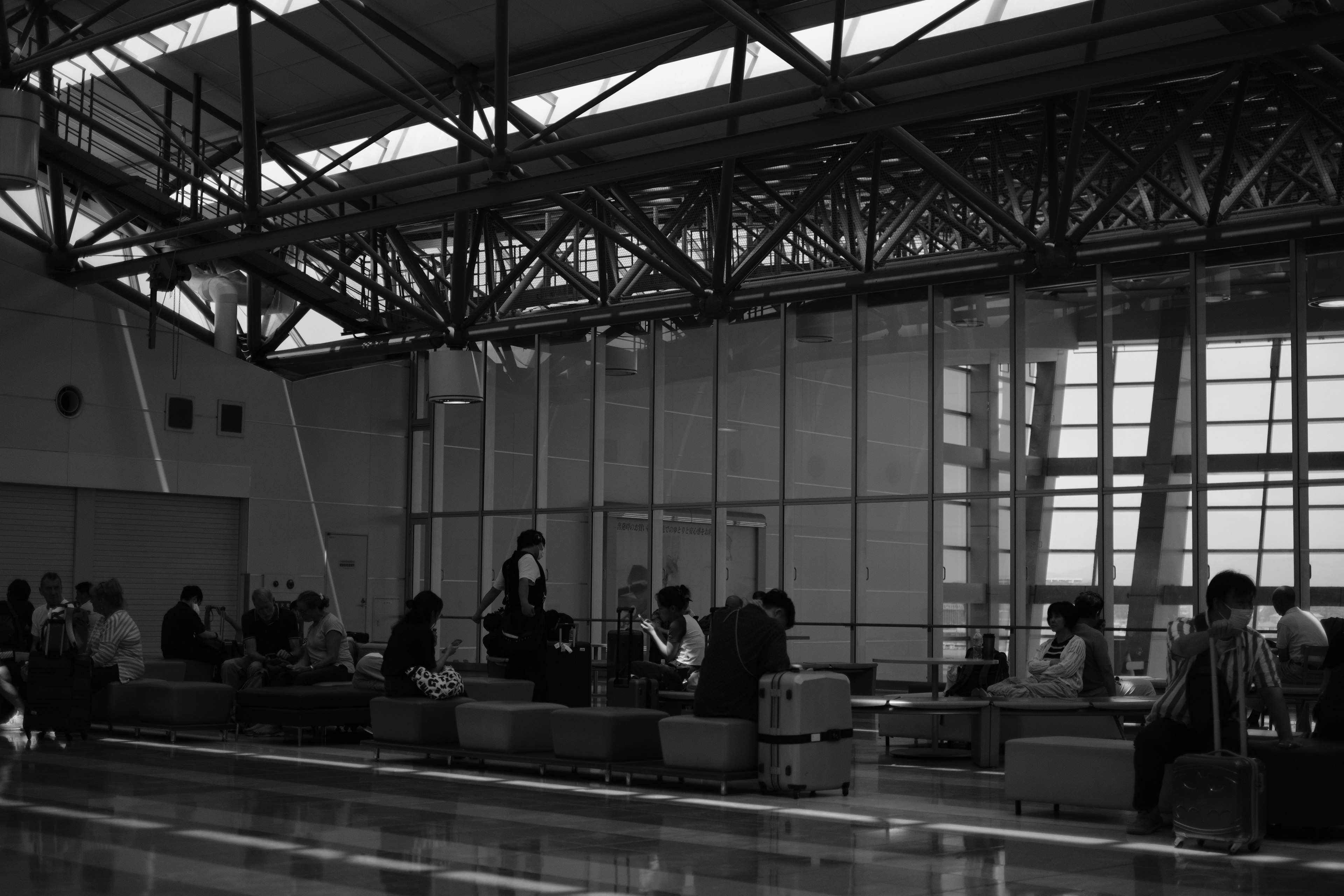 Black and white image of people sitting in an airport waiting area