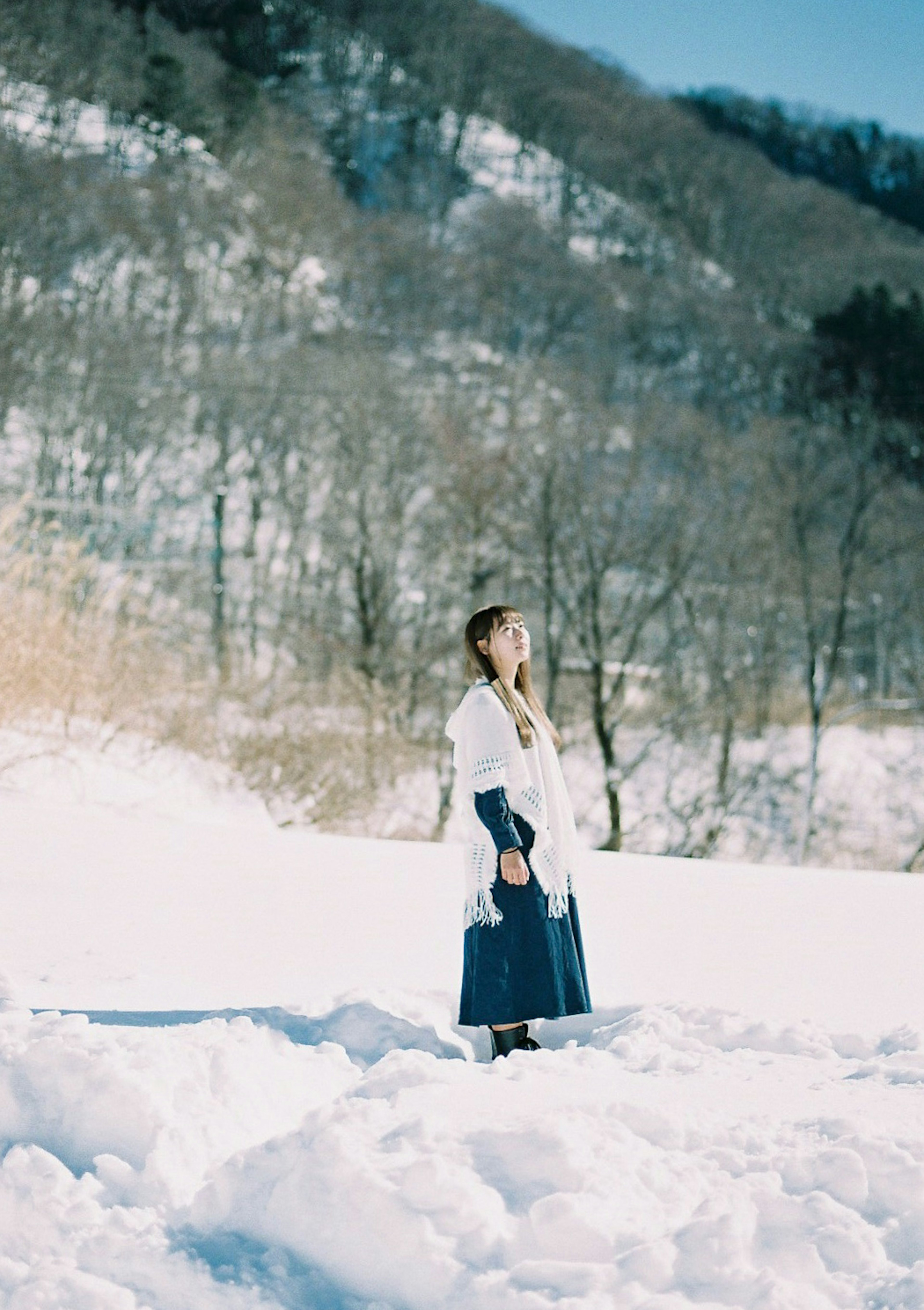 Femme debout dans la neige portant un manteau blanc et une jupe bleue paysage d'hiver