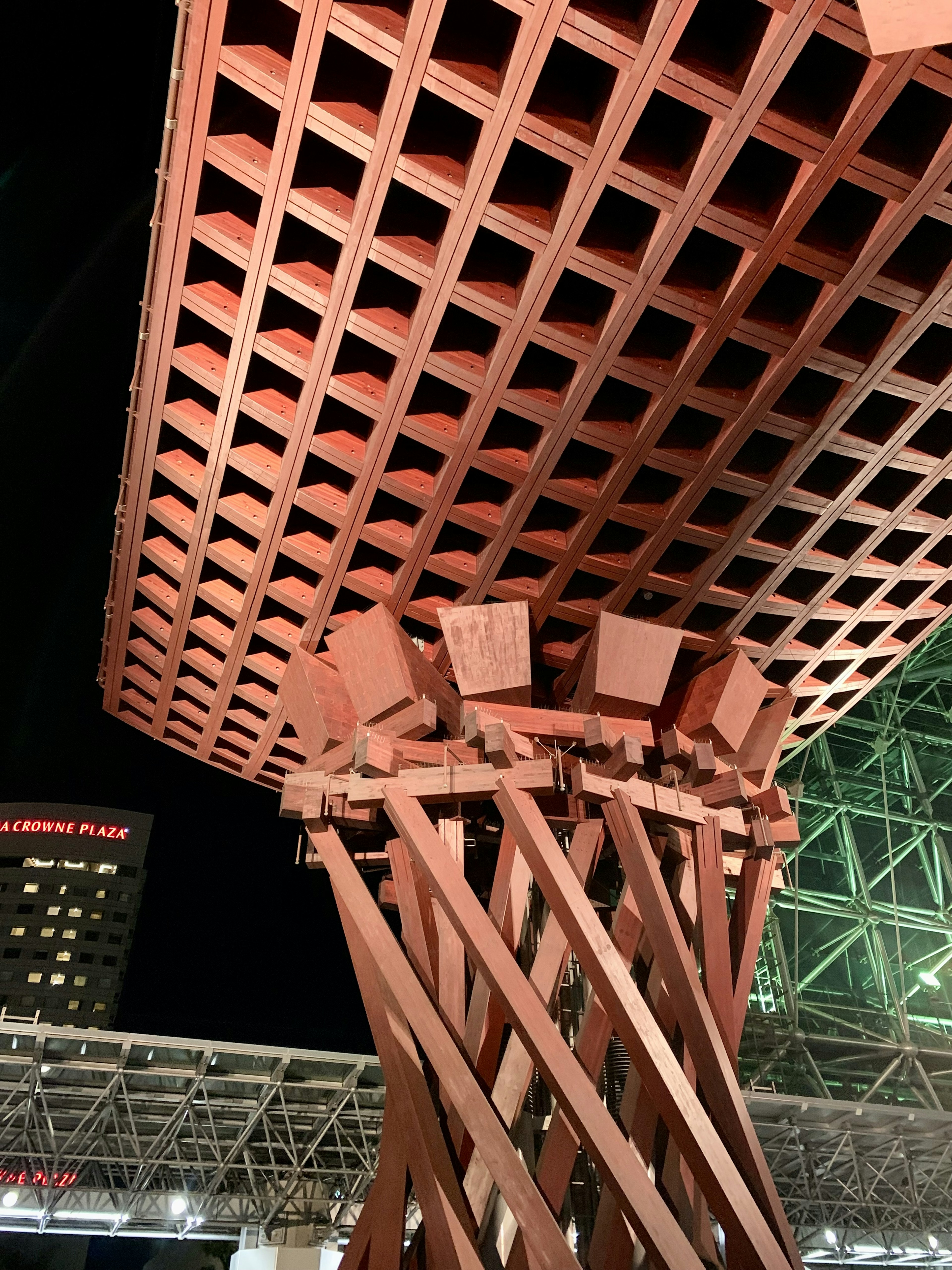 Unique design of a red roof structure supported by wooden beams at night