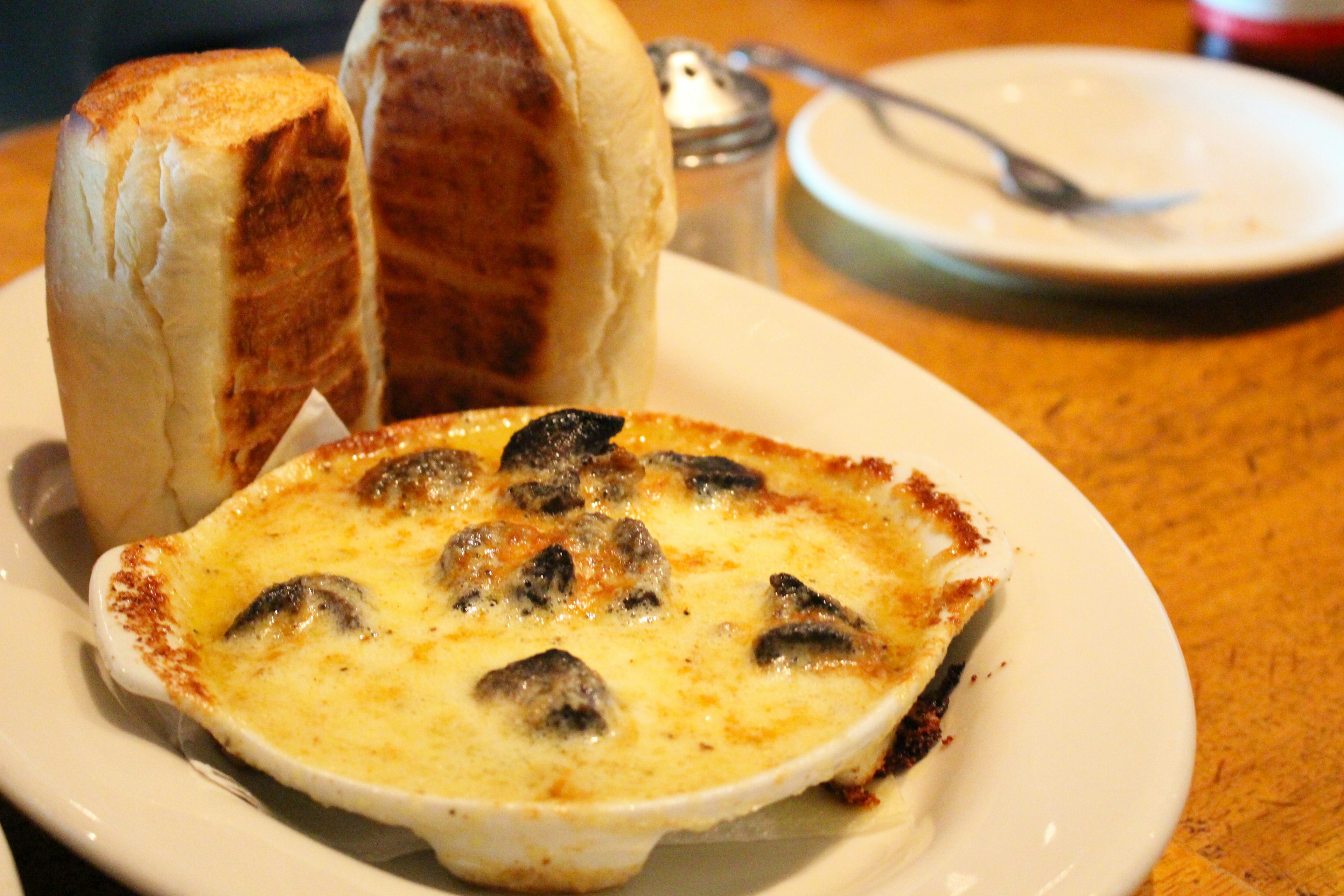 Baked bread rolls alongside creamy mushroom gratin served in a dish