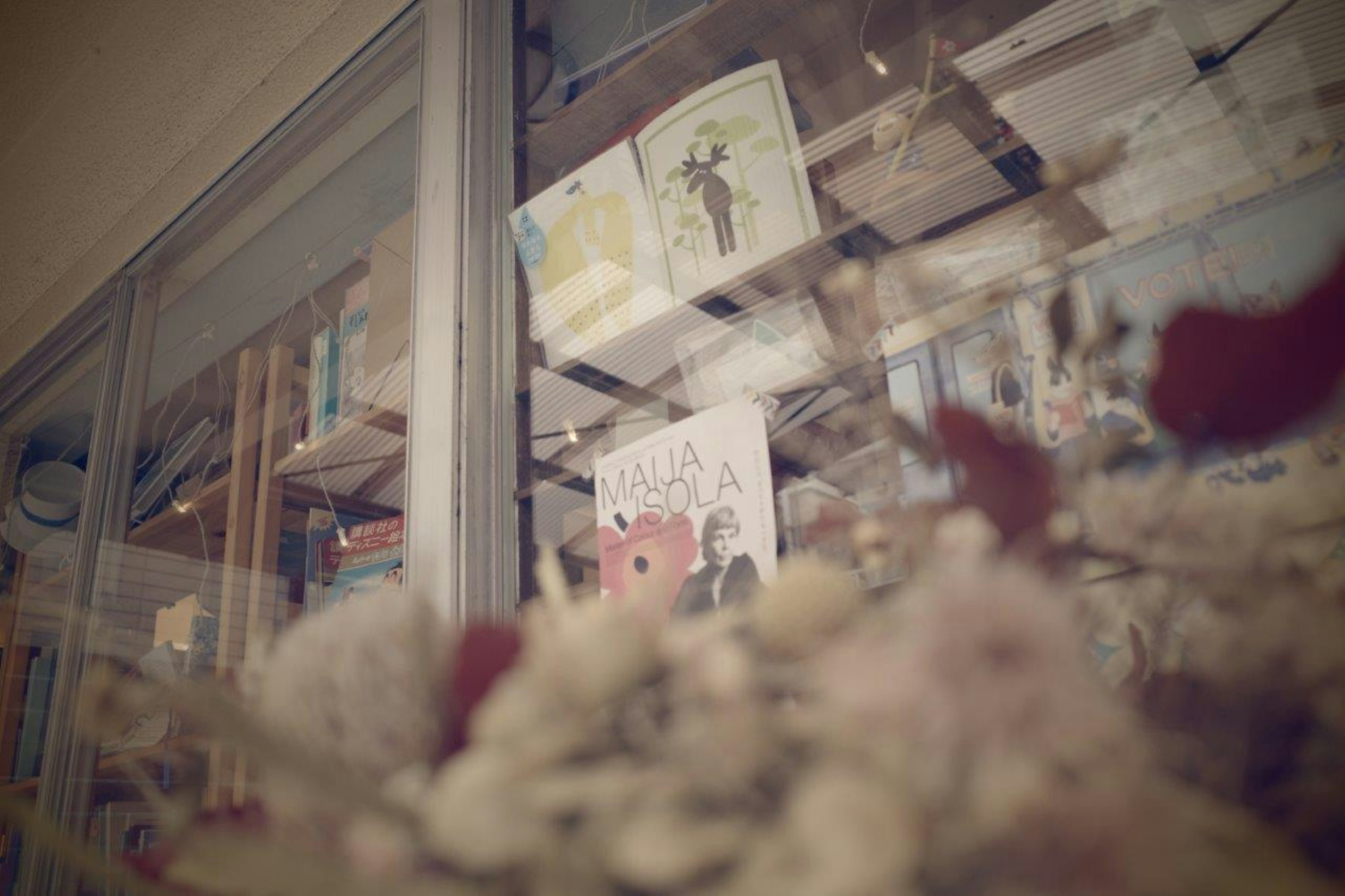 View through a window showcasing books and floral arrangement