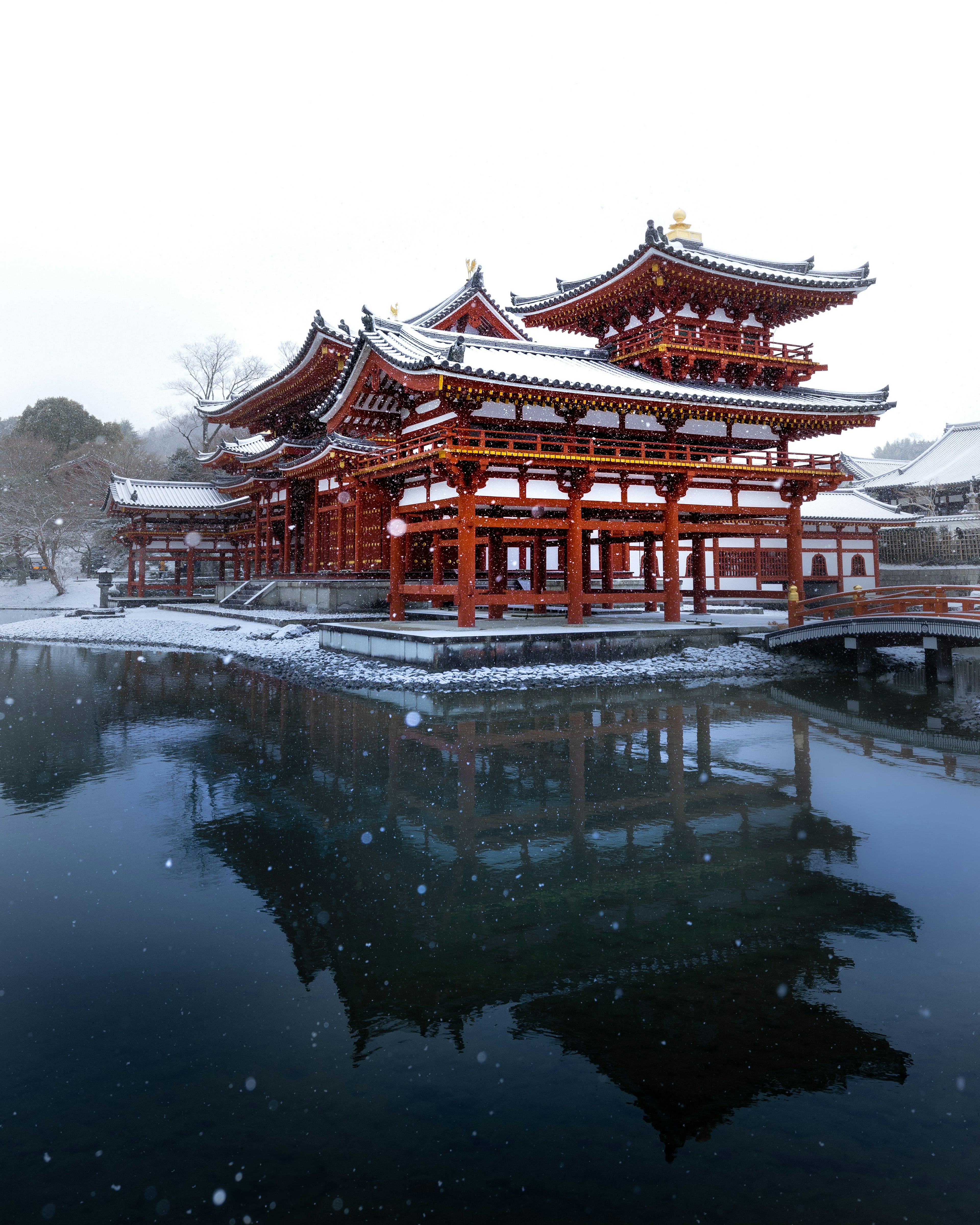 Bangunan tradisional Jepang yang tertutup salju di tepi kolam yang tenang