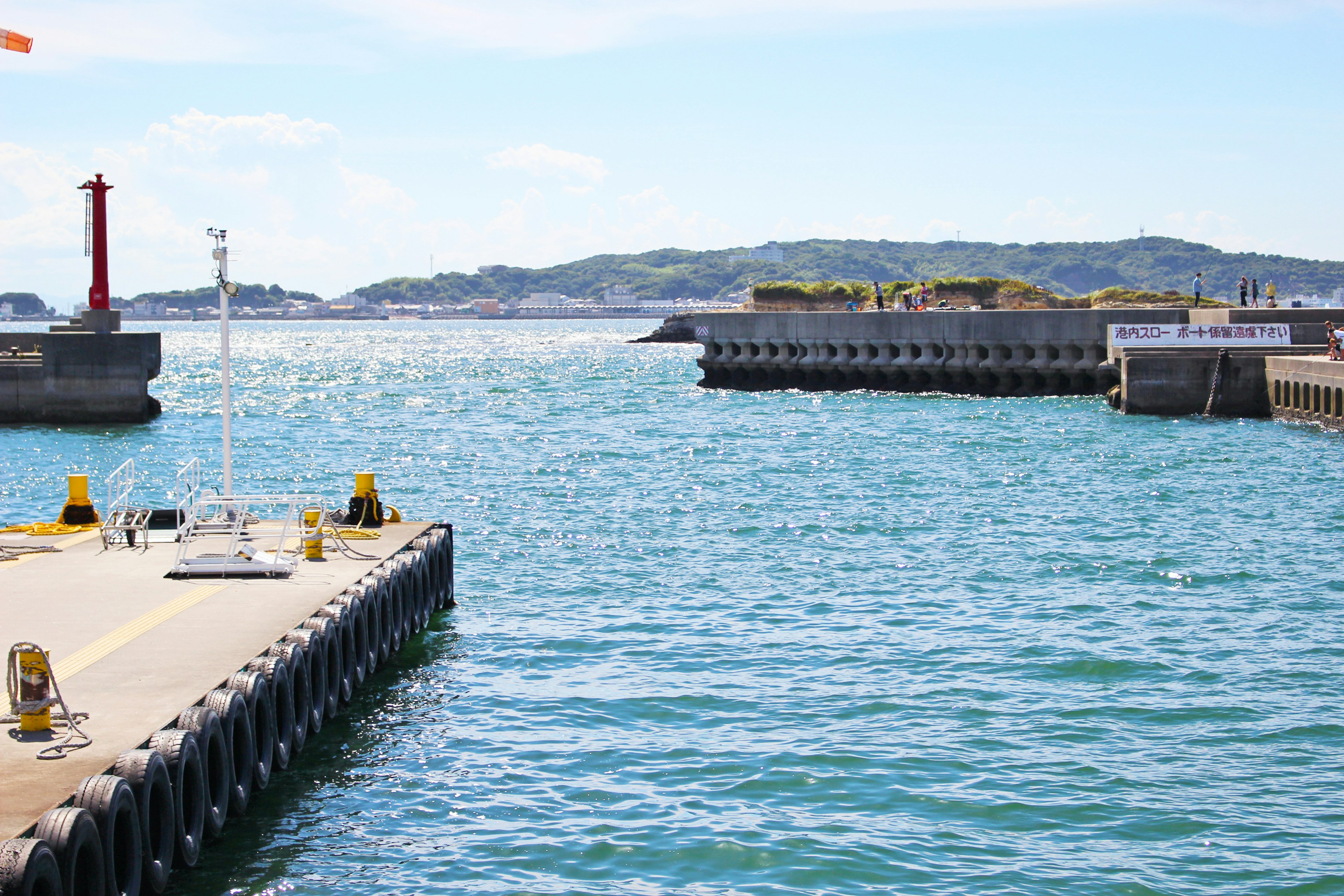 Vista panoramica del mare blu e del porto con faro e frangiflutti visibili