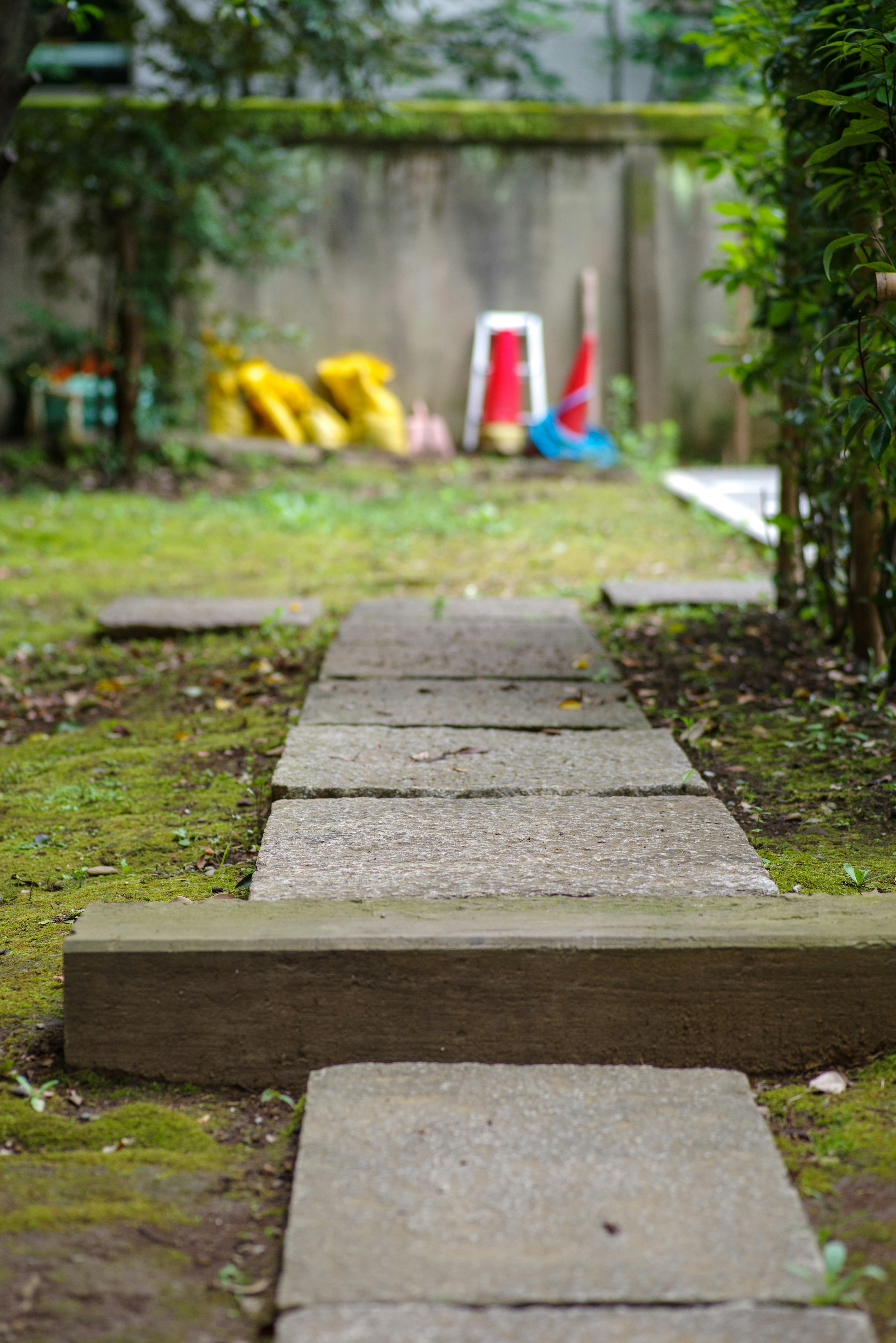 Chemin en pierre dans le jardin avec de la verdure et des objets colorés en arrière-plan