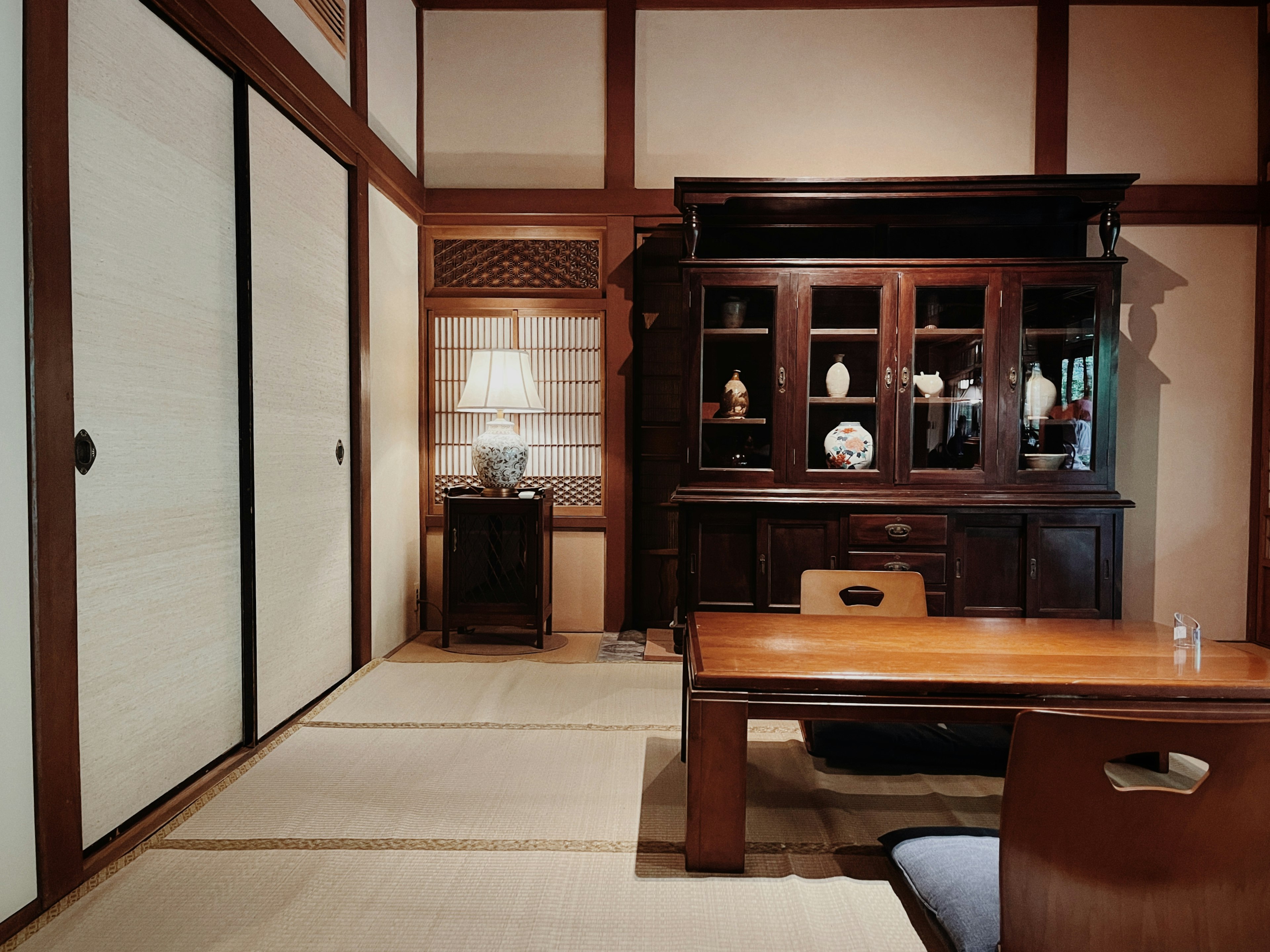 Image of a traditional Japanese room with wooden furniture tatami flooring and a glass display cabinet soft lighting