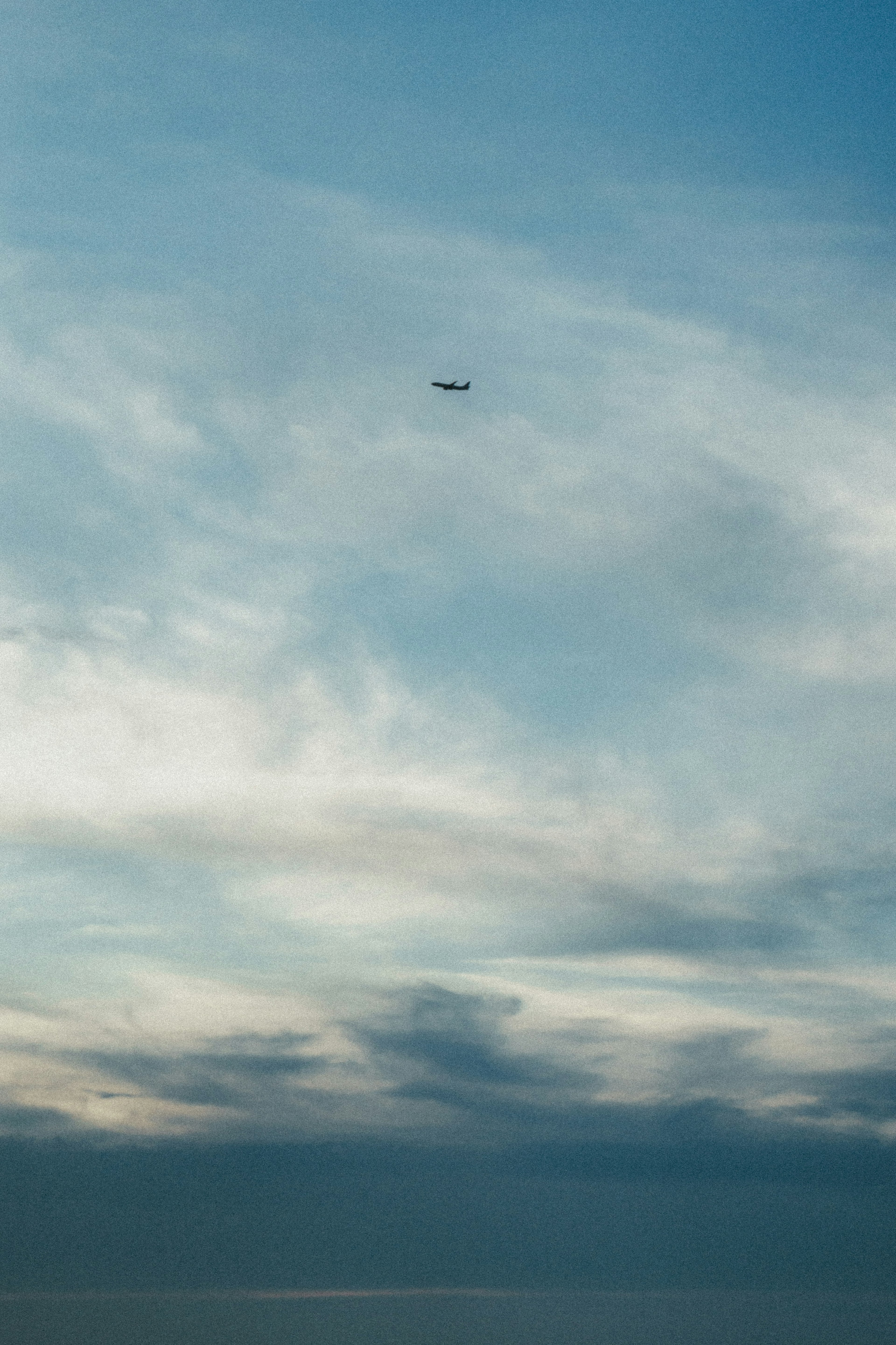 青い空と雲の上を飛ぶ飛行機