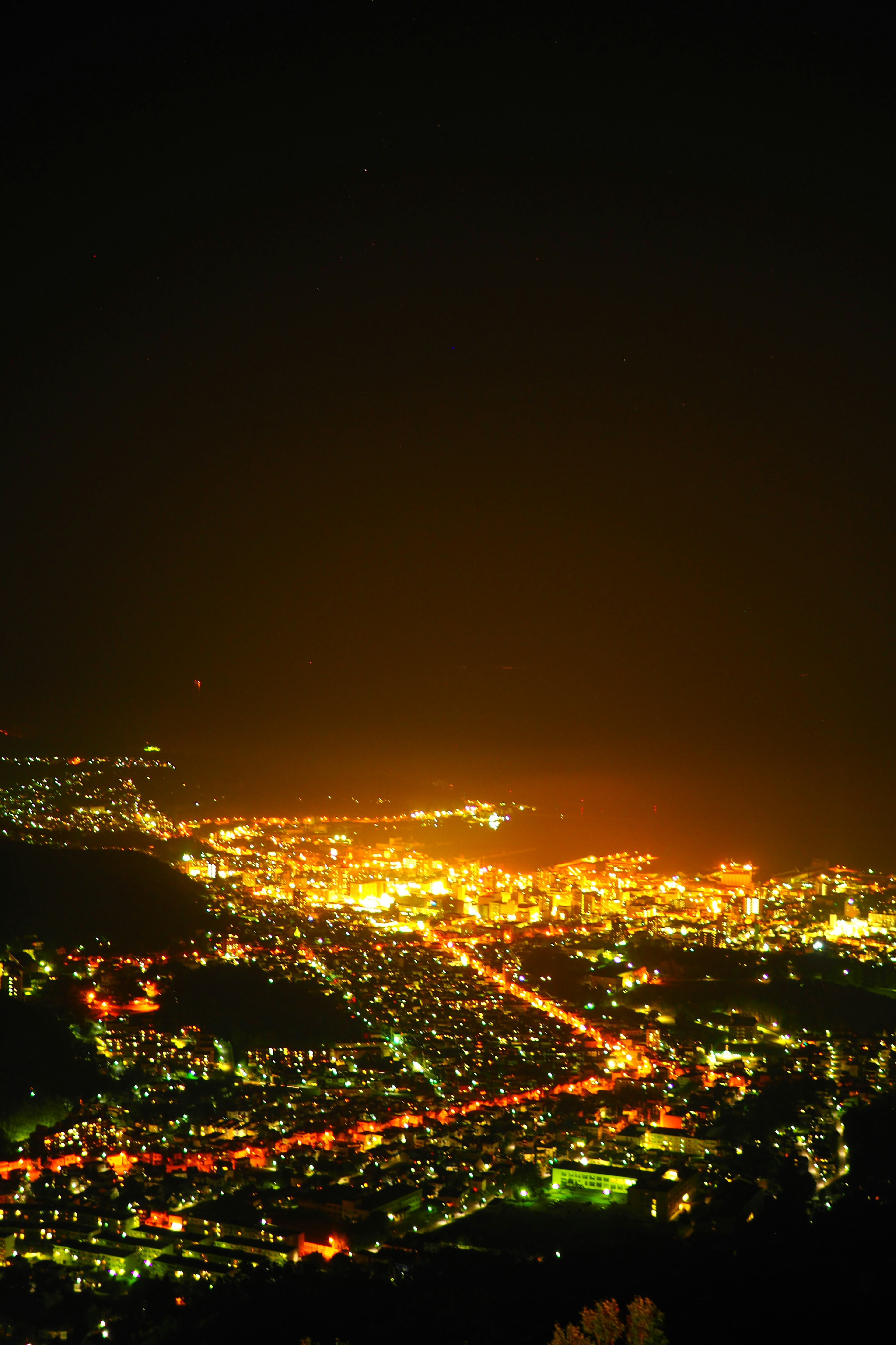 Panoramablick auf eine Stadt bei Nacht mit hellen Straßenlichtern und beleuchteten Straßen