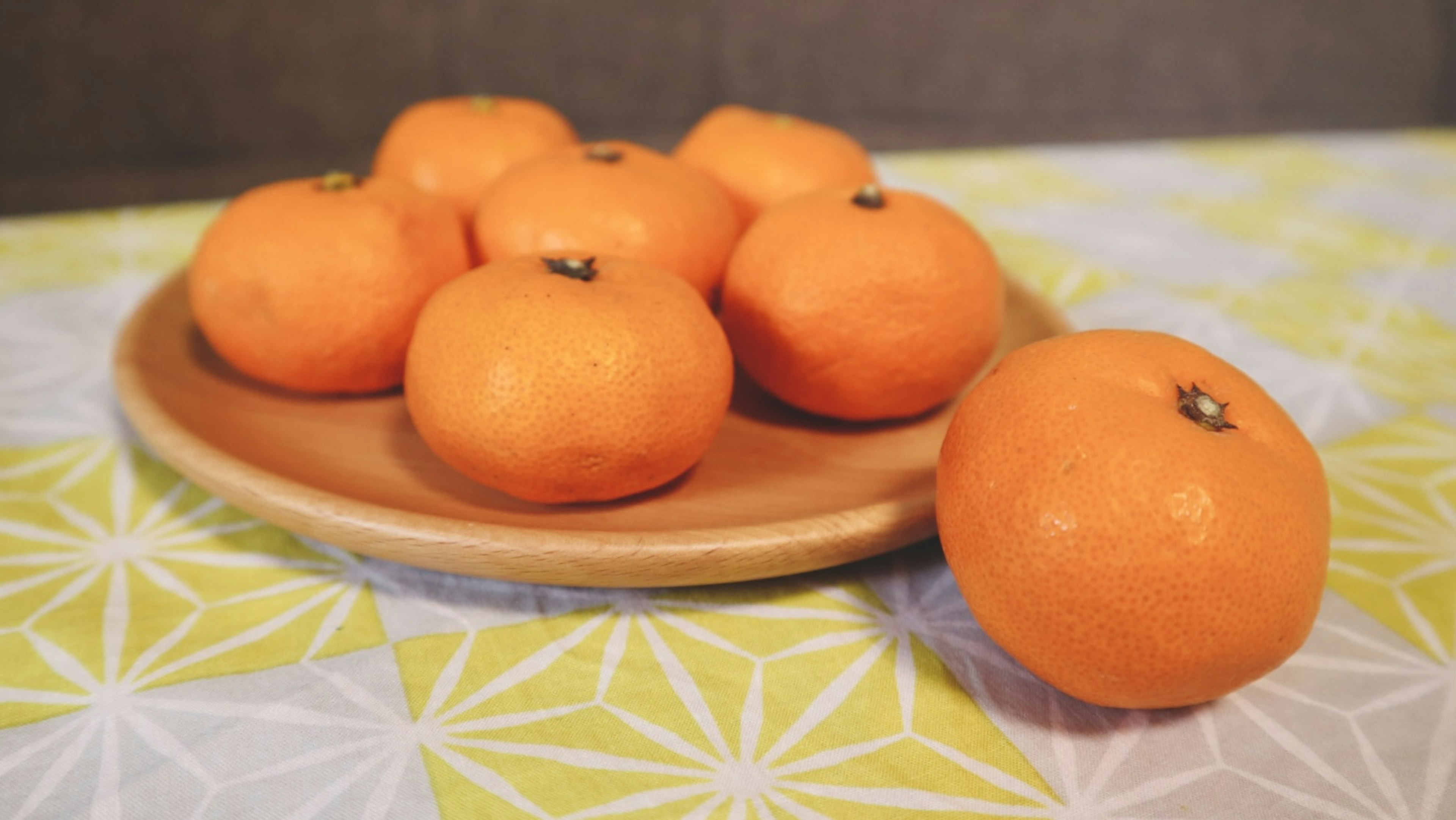 Un plato de mandarinas naranjas sobre un mantel estampado