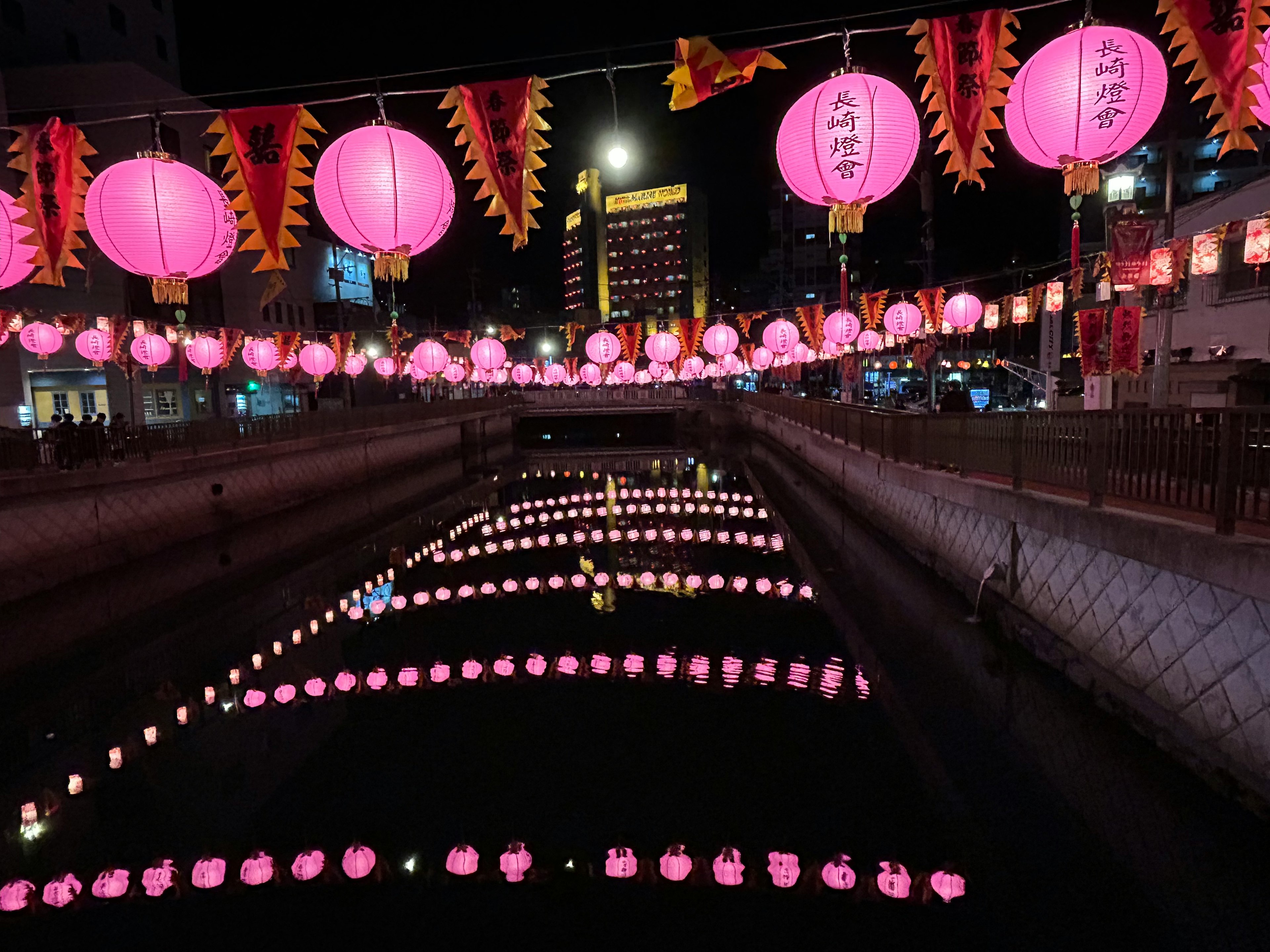 夜の川に浮かぶピンクのランタンと光の反射