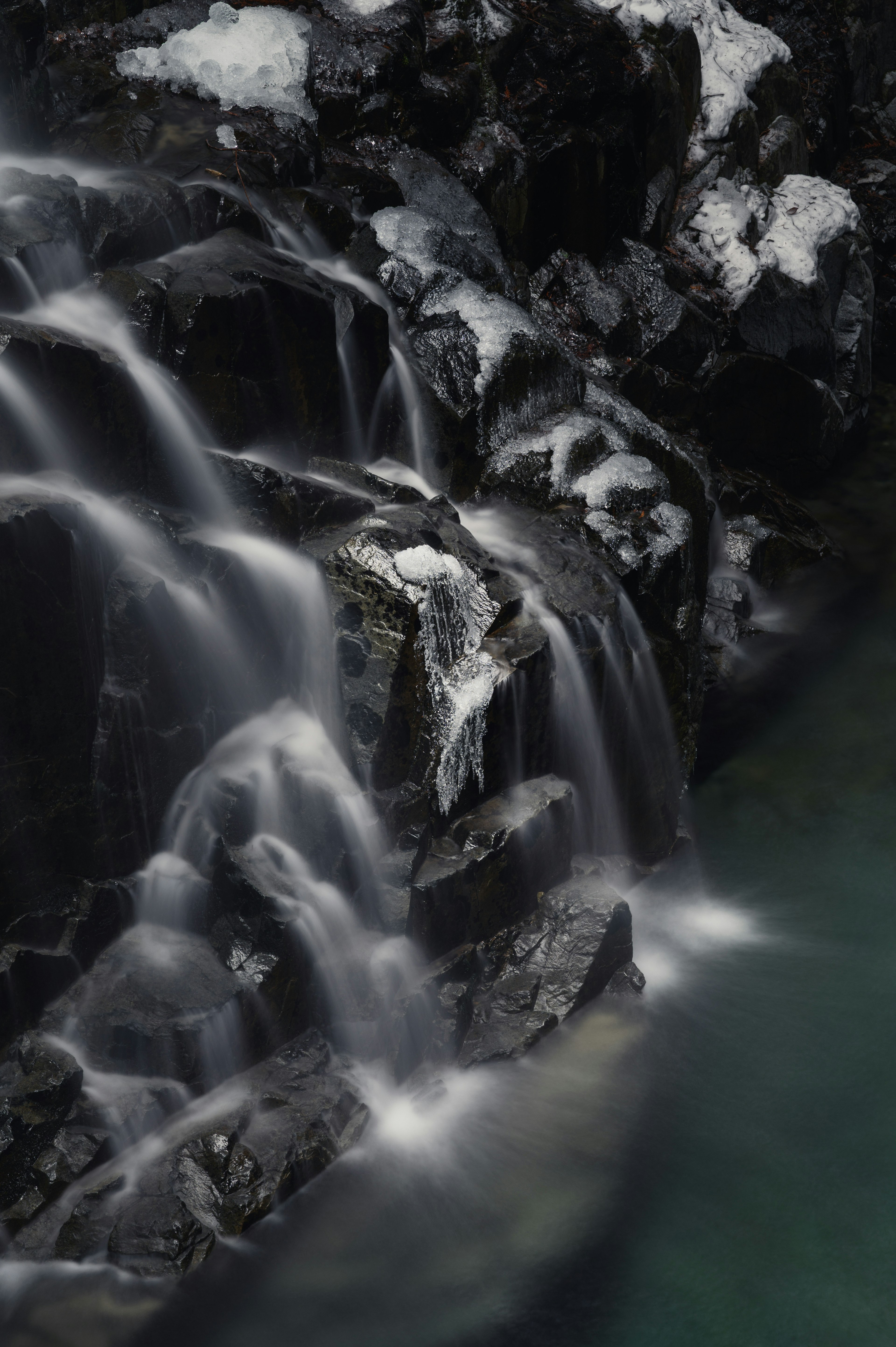 流动的瀑布在岩石上，背景深色，水面光滑