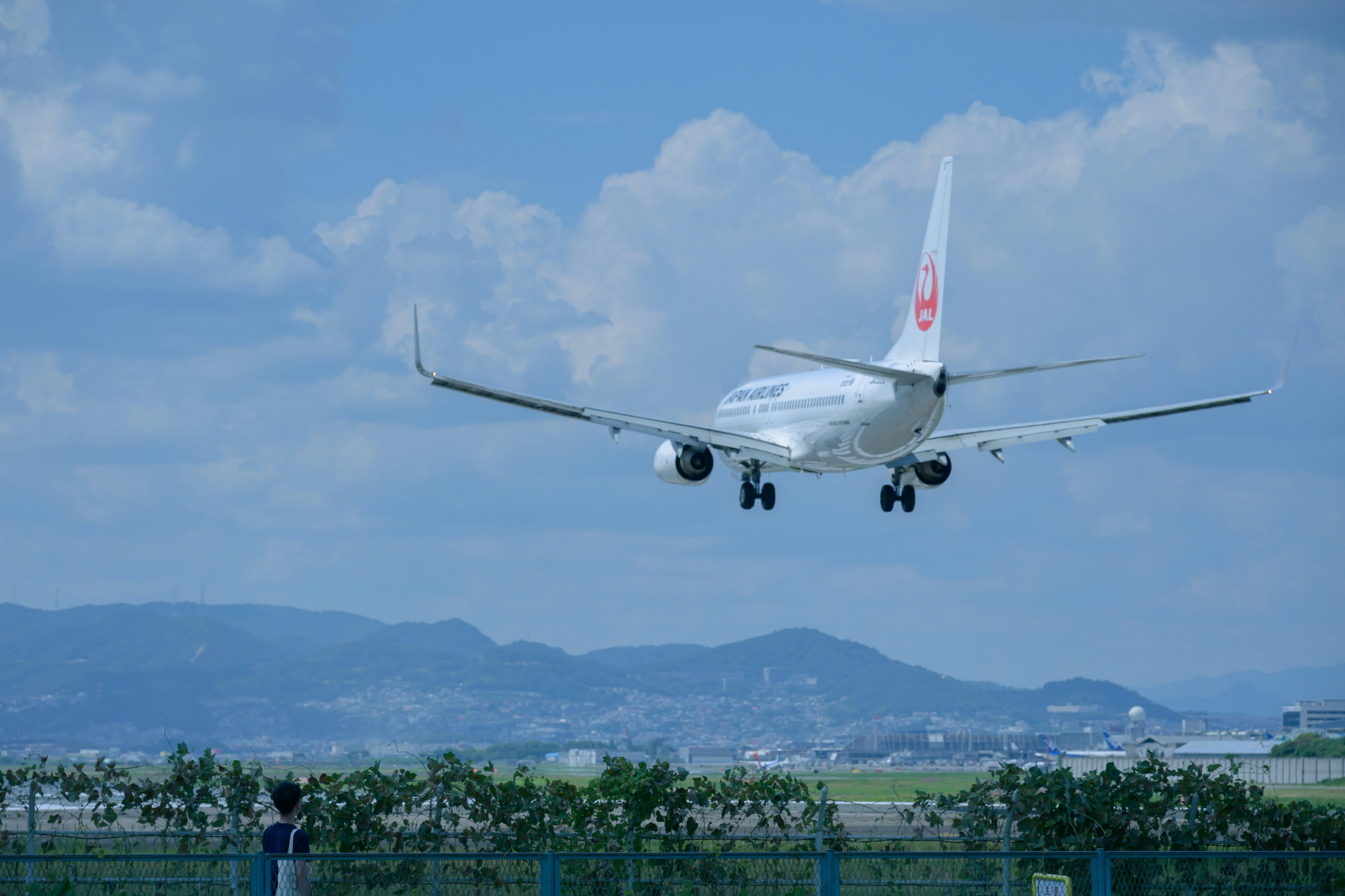 青空の下で着陸する飛行機と山の背景