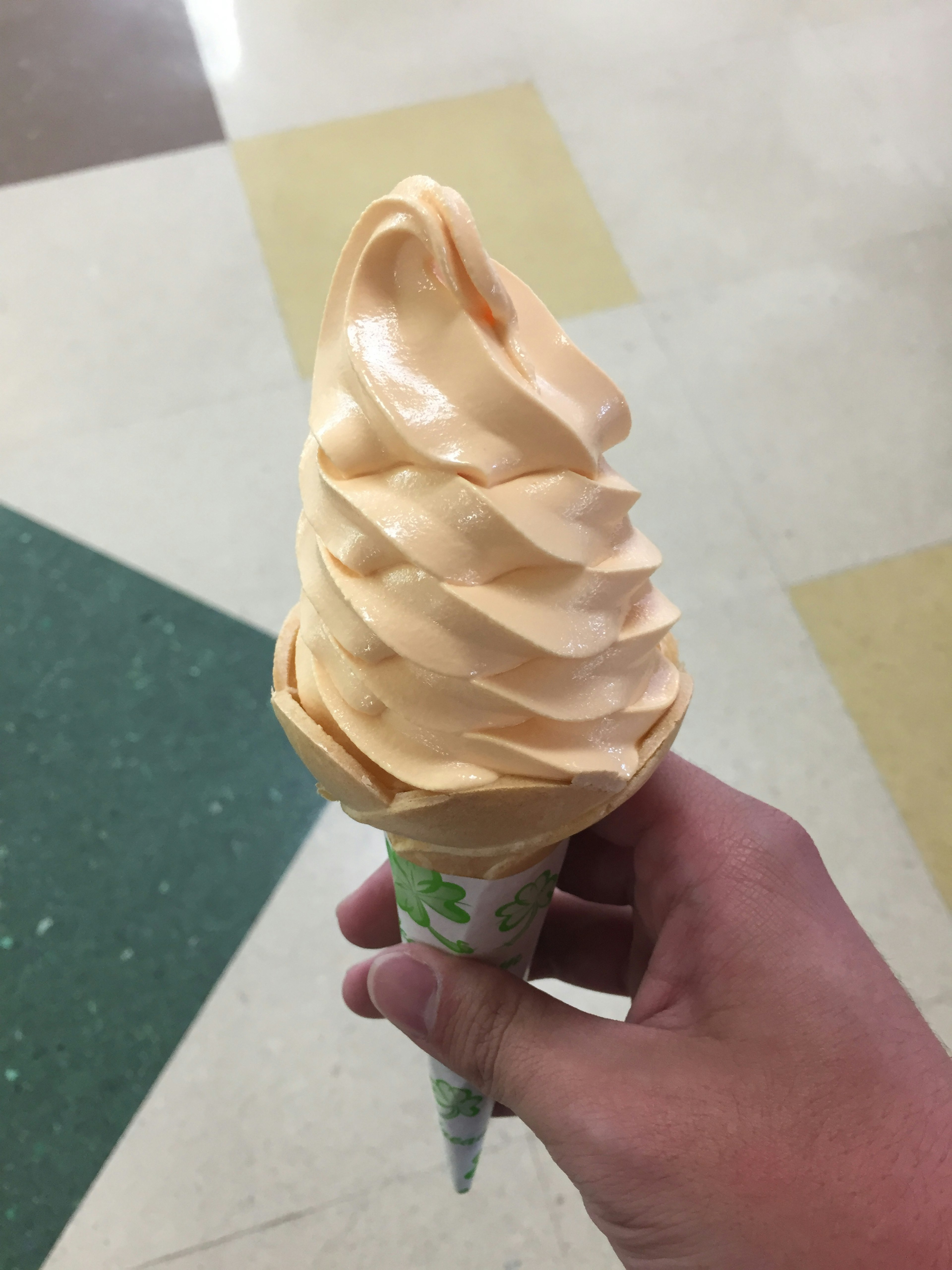 Una mano sosteniendo un helado suave naranja en un cono