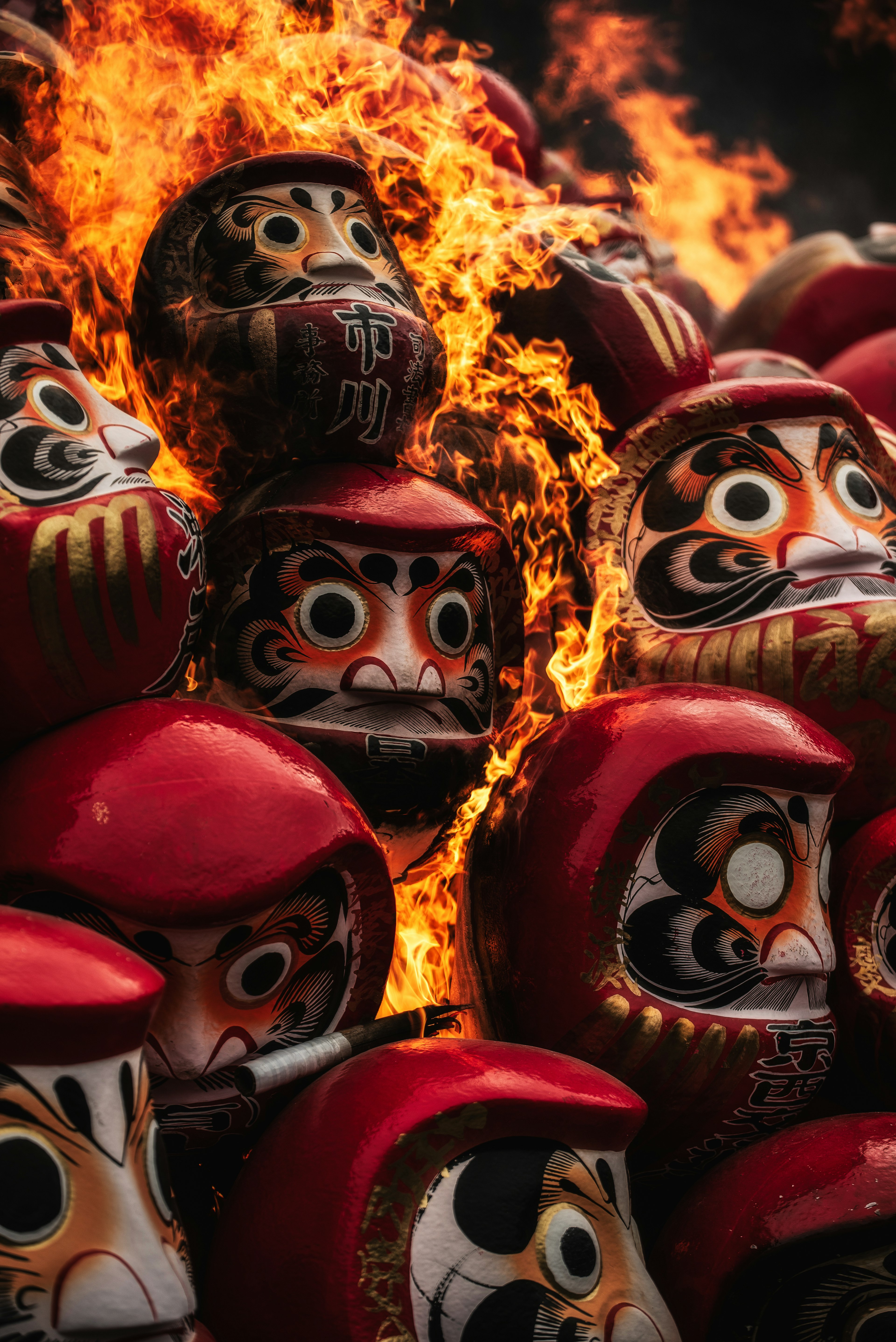 Boneka Daruma bertumpuk di tengah api