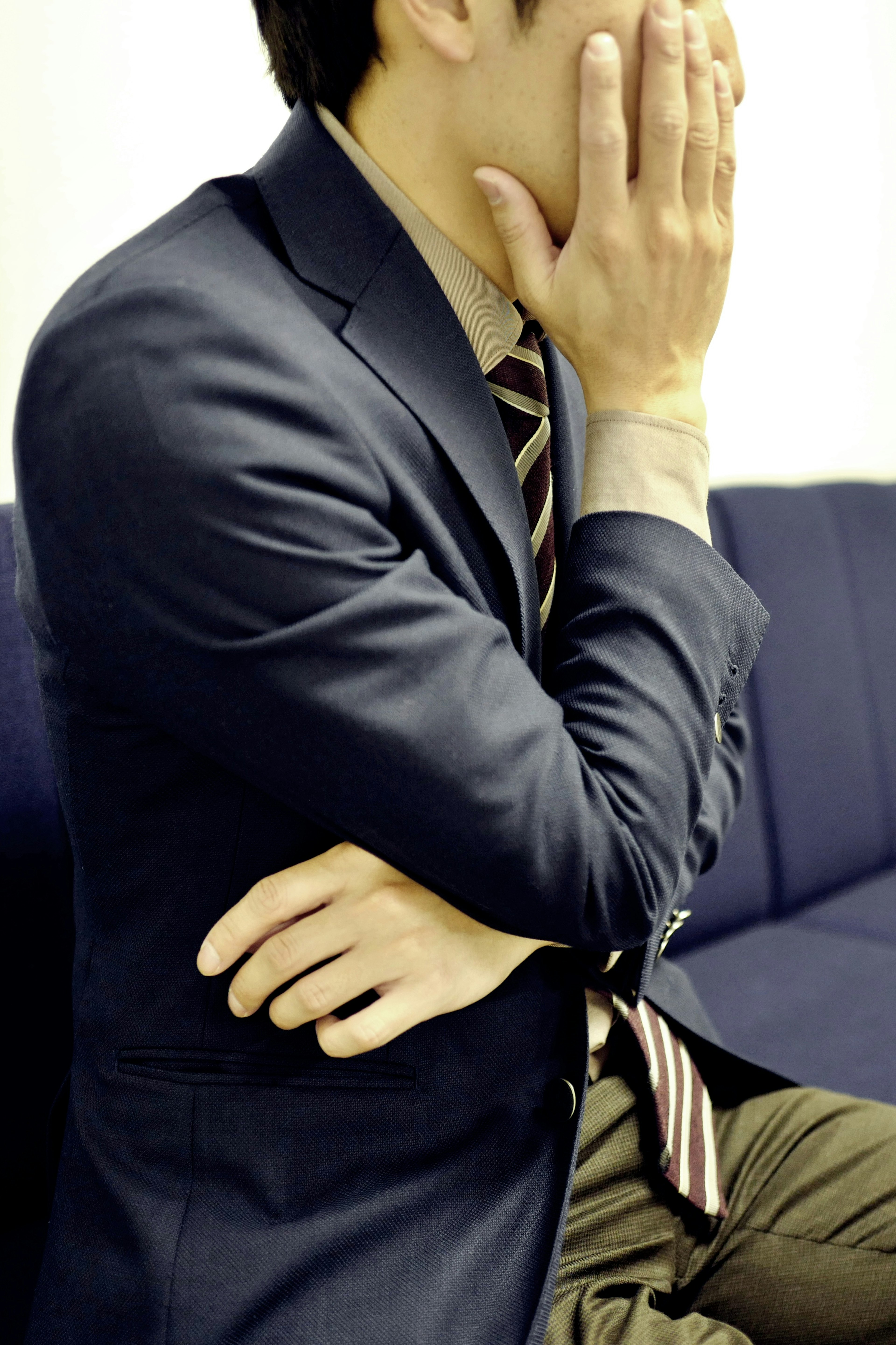 A man in a suit covering his face with his hand