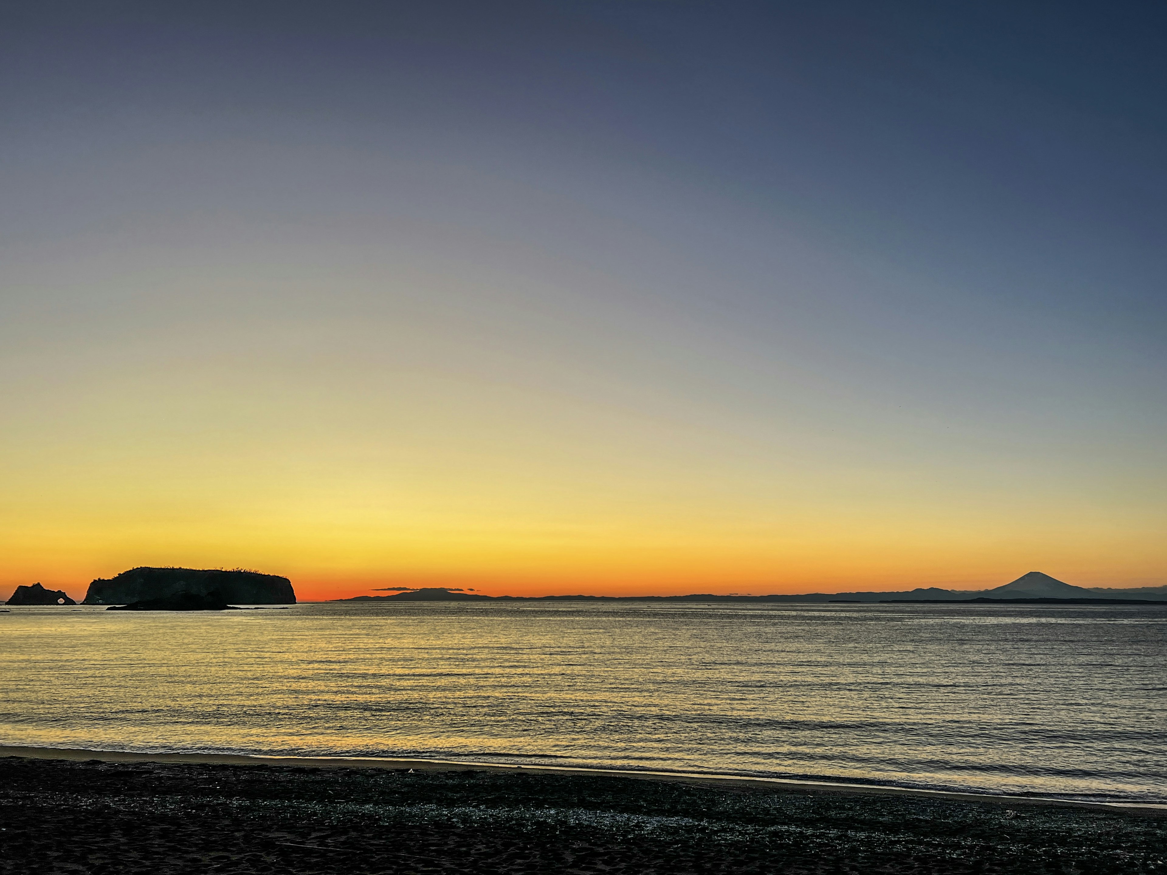 Hermoso atardecer iluminando el mar con una montaña a lo lejos