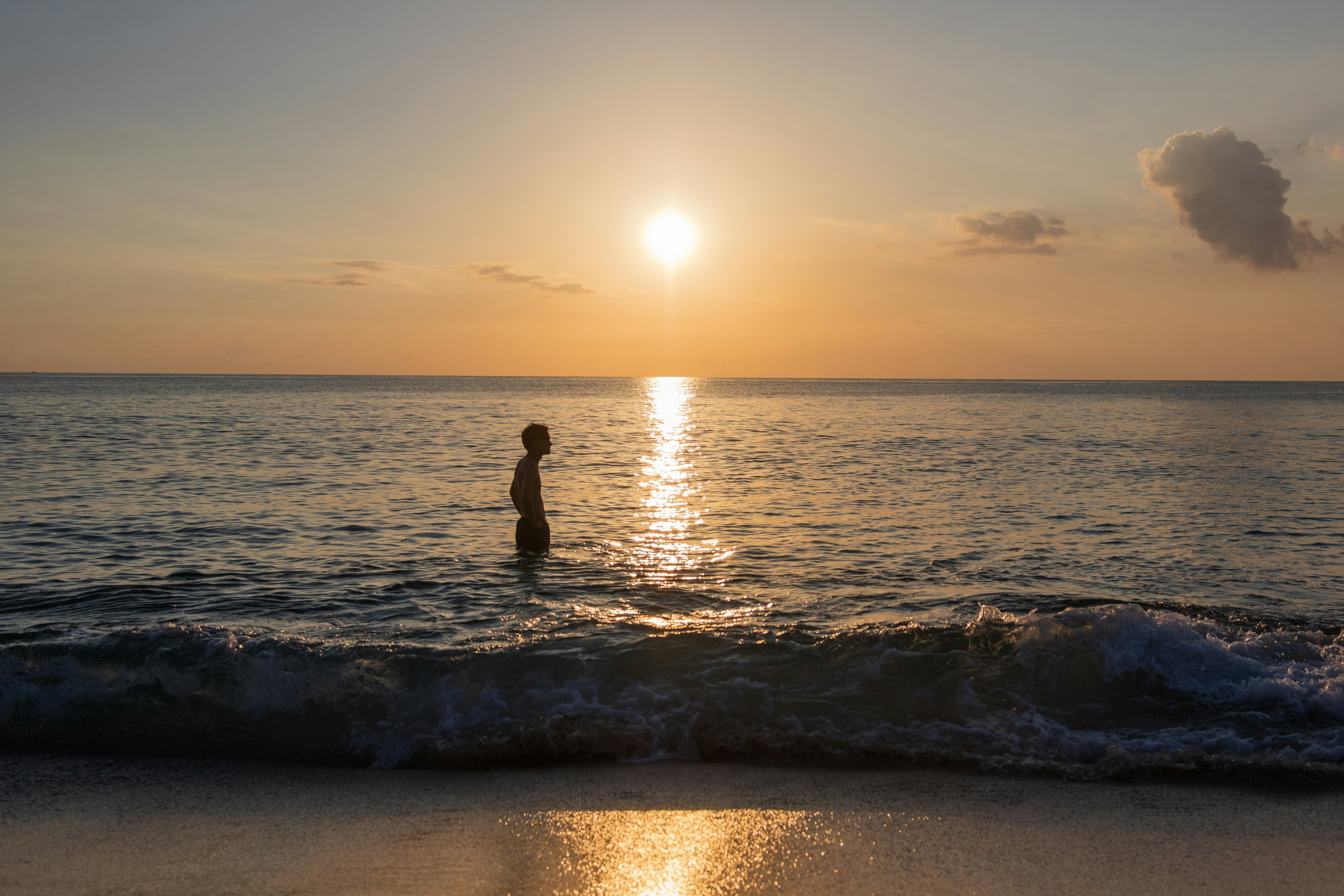 Silhouette di una persona in piedi nell'acqua contro un tramonto