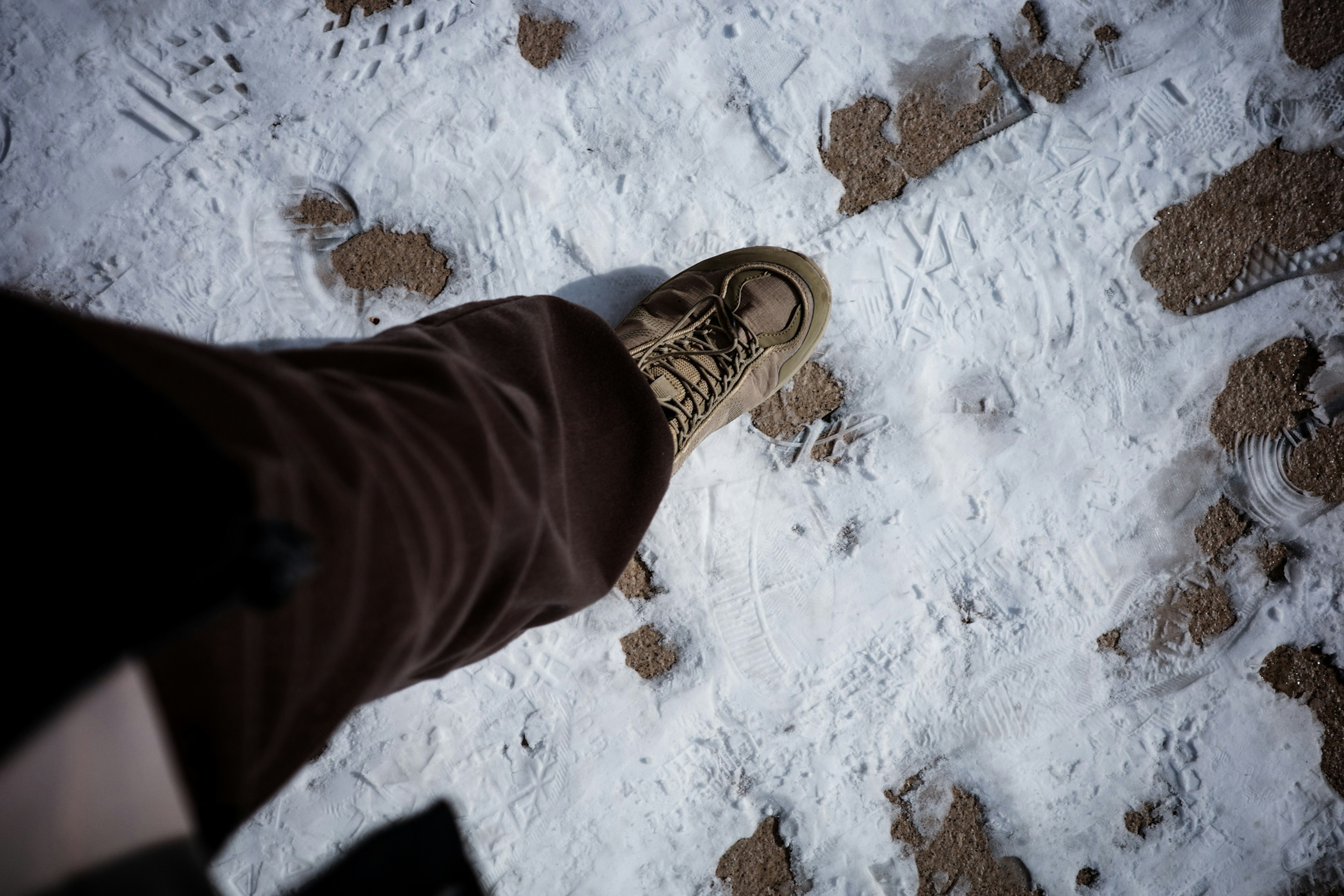 Gros plan d'un pied marchant sur la neige avec une chaussure