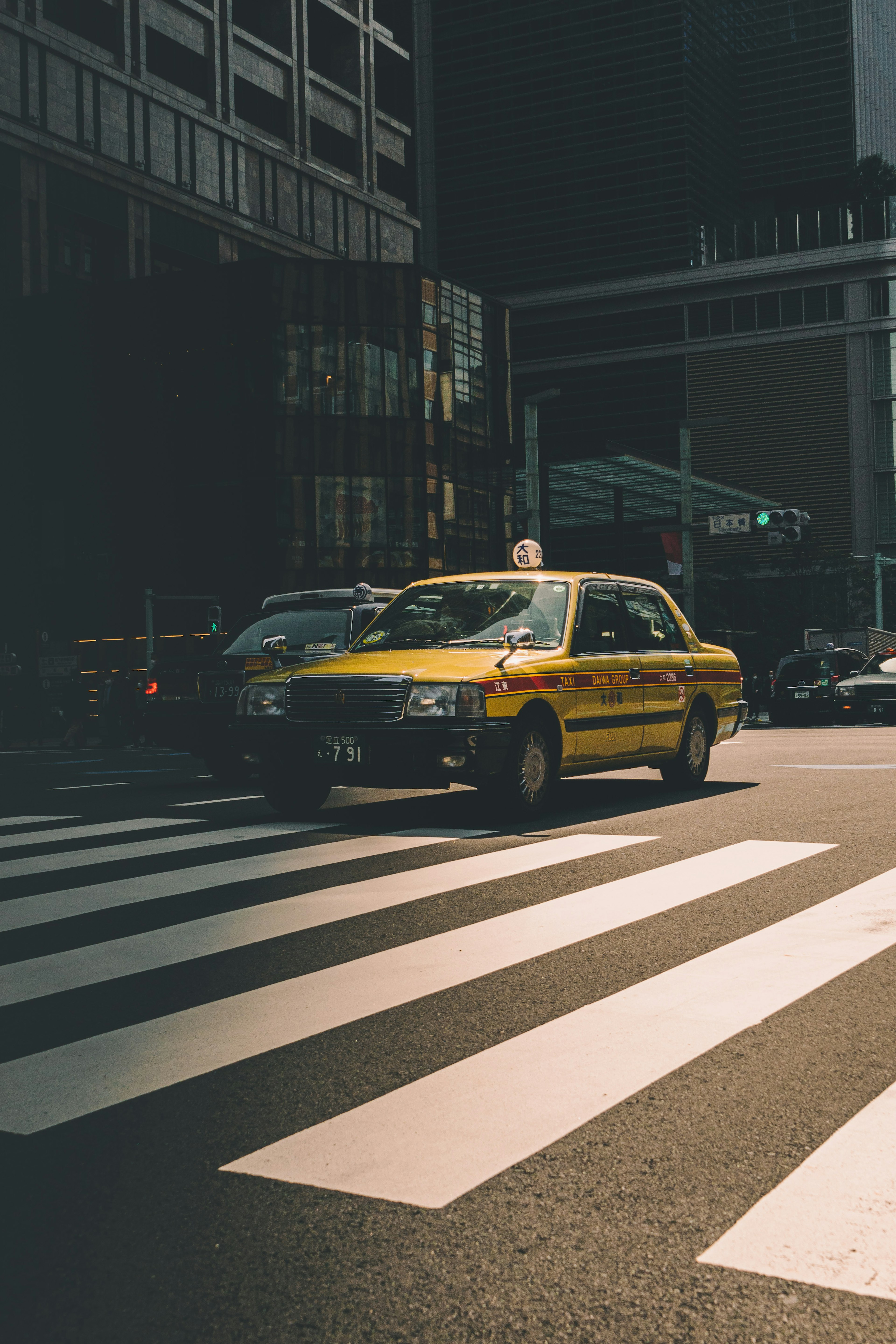 Yellow taxi crossing a pedestrian crosswalk in an urban setting