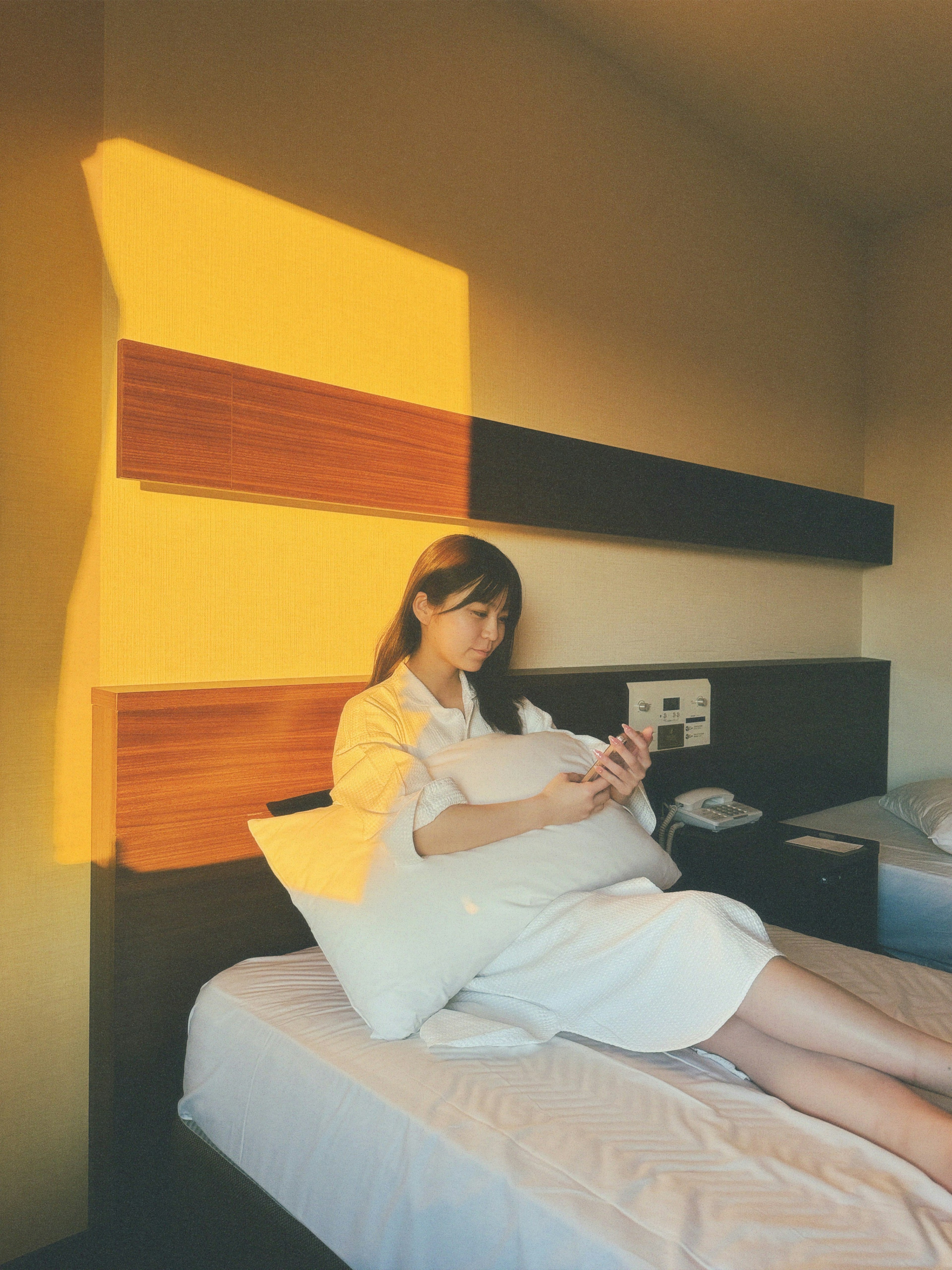 Pregnant woman sitting on a bed with warm light