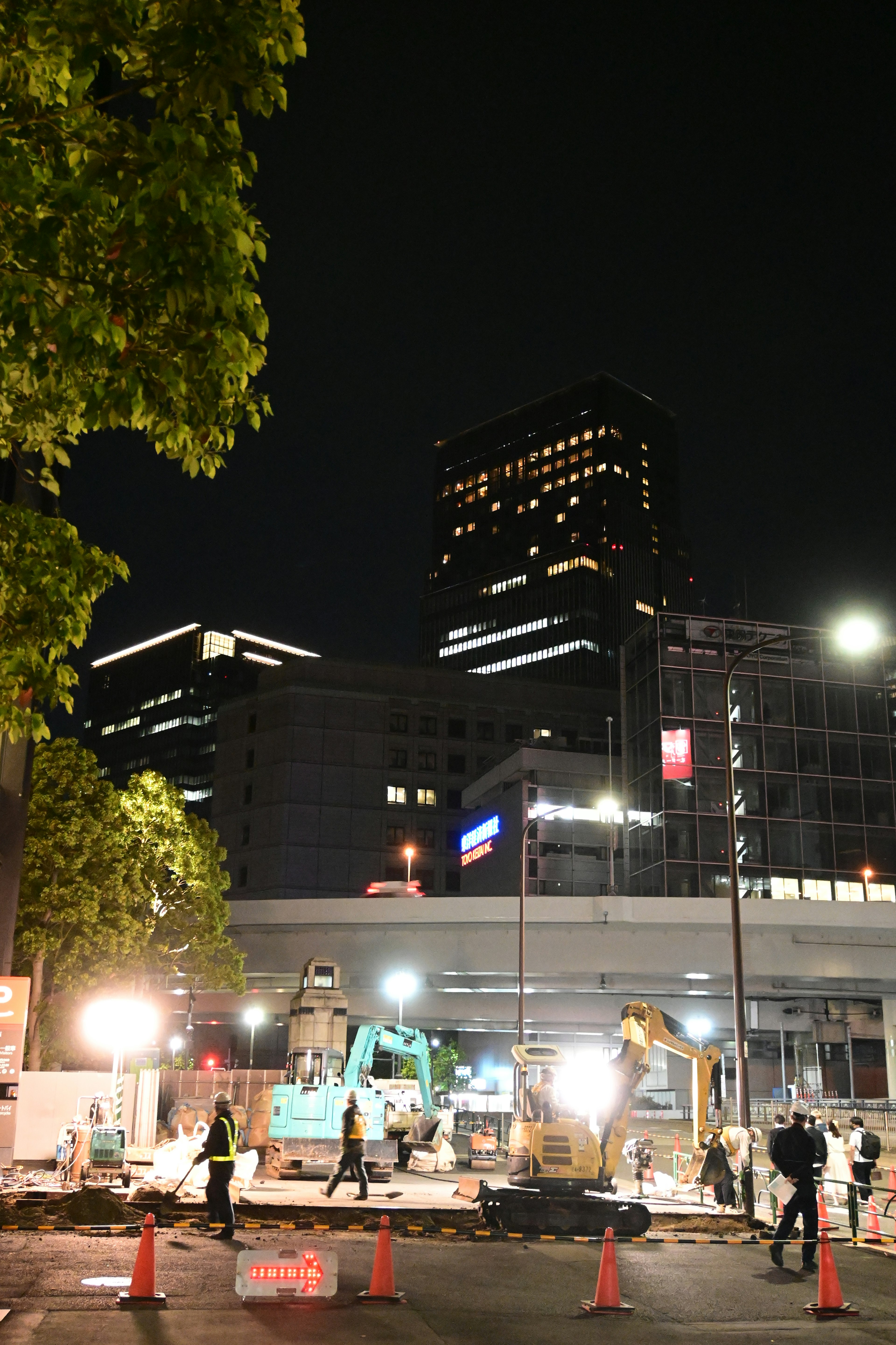 Sitio de construcción urbano nocturno con edificios al fondo