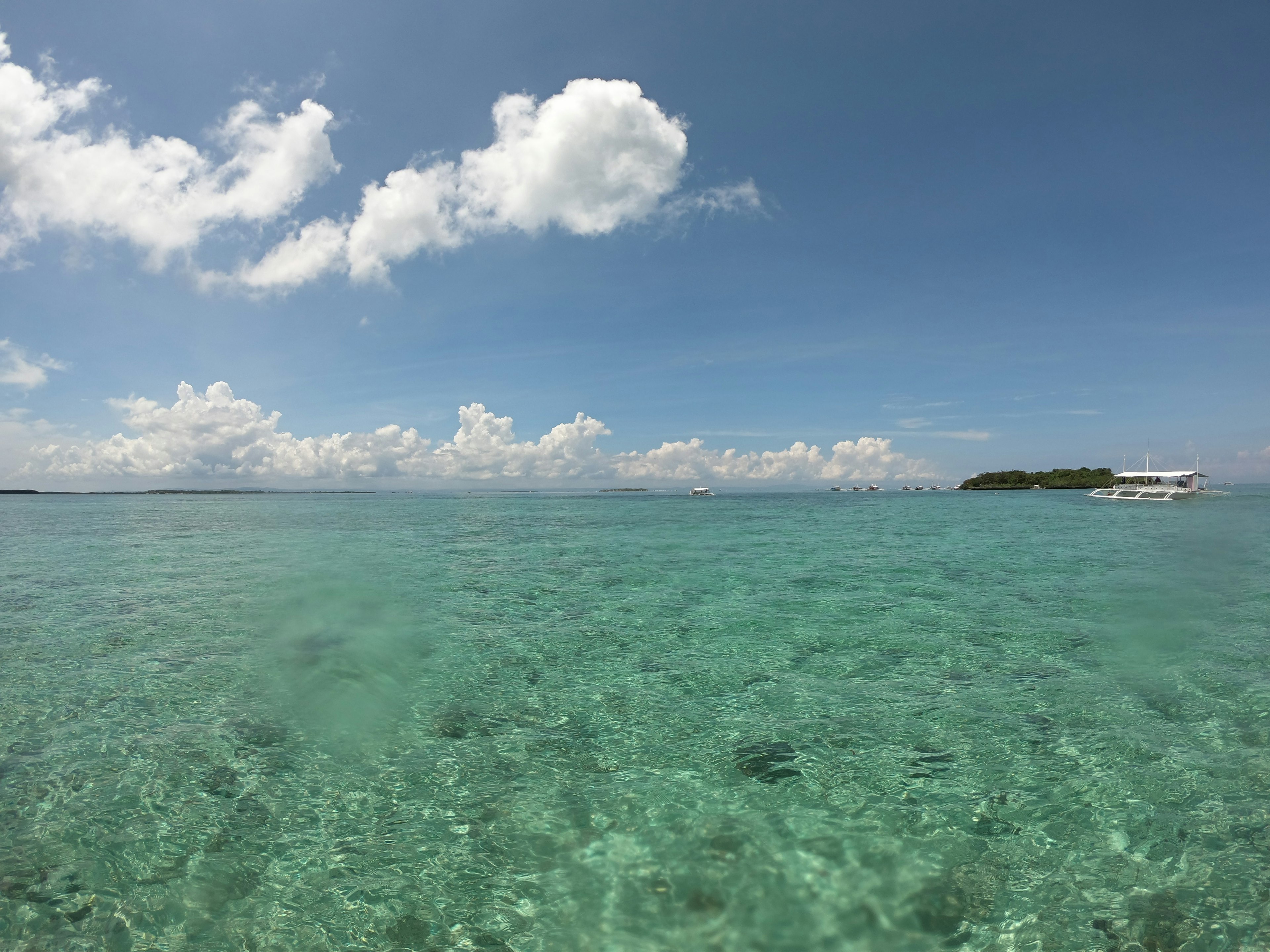 Clear turquoise waters under a blue sky with white clouds